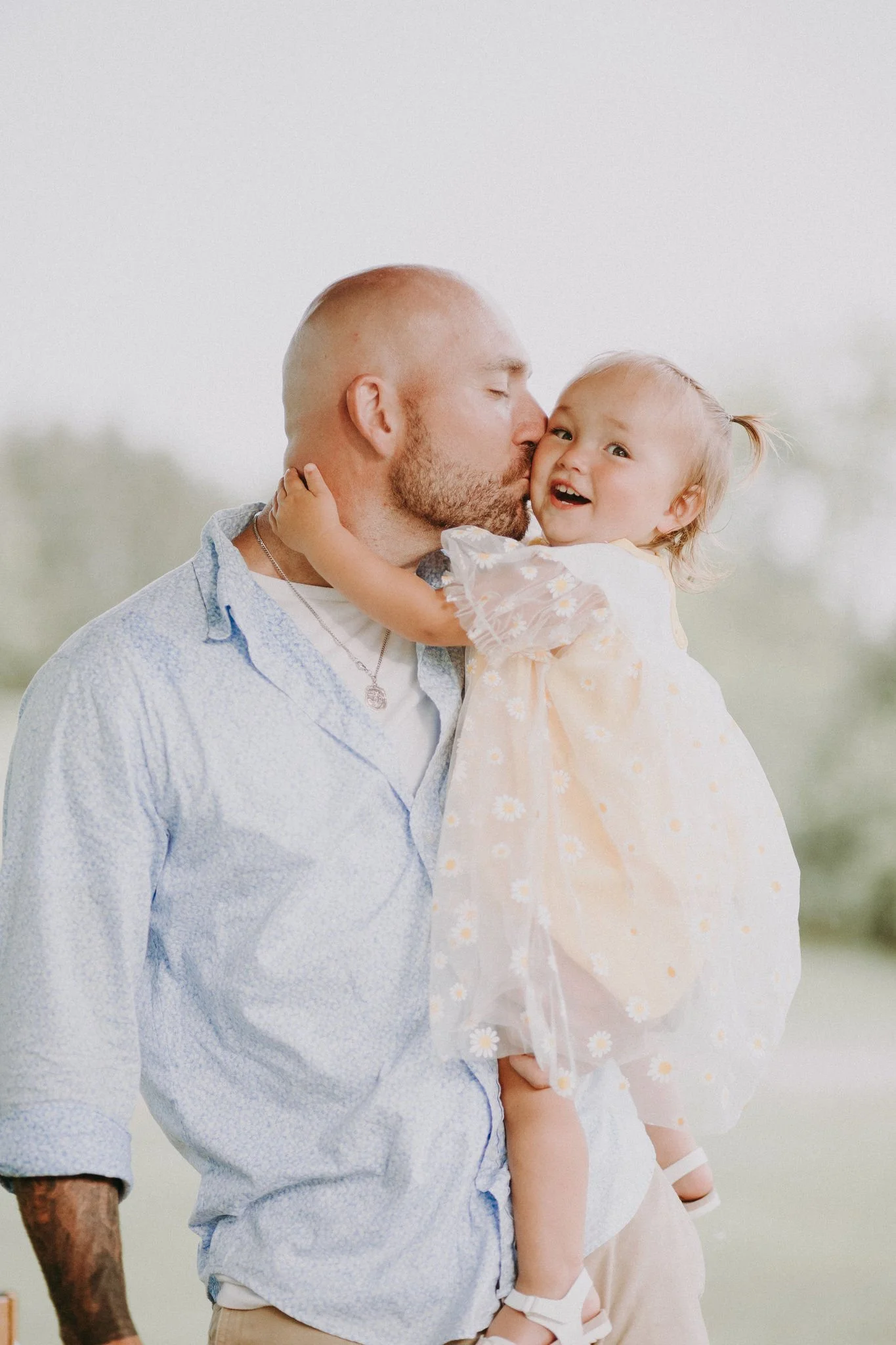 A parent holding their child and kissing their cheek 