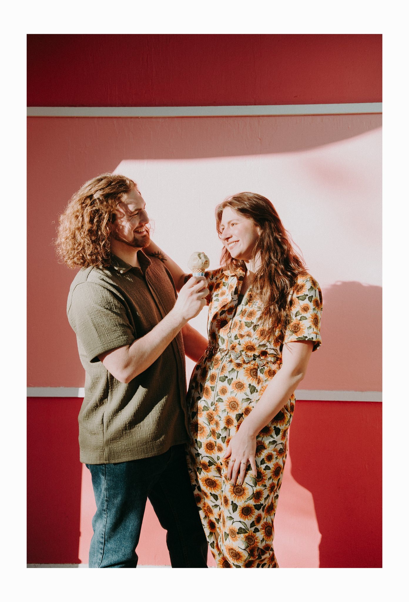 A couple smiling as one holds an ice cream cone out to the other 