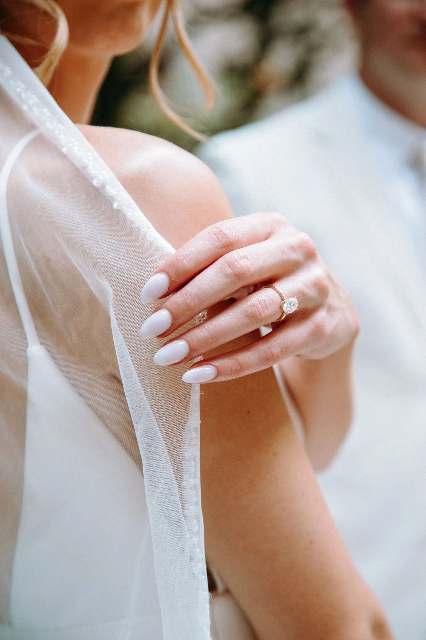 A person adjusting their veil and showing off an engagement ring