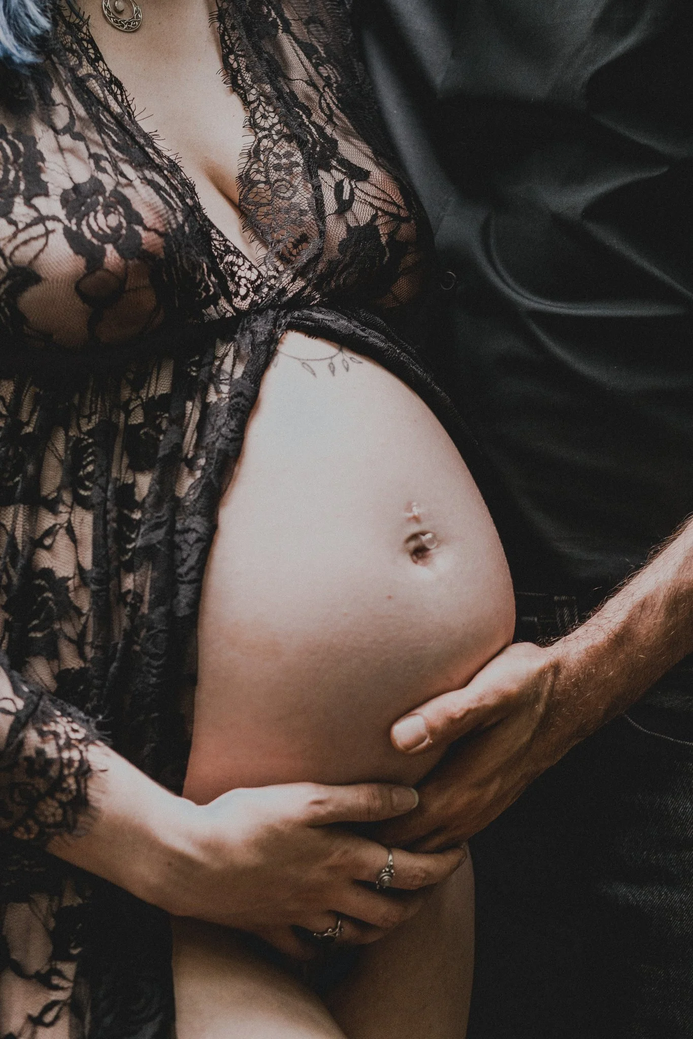A pregnant person and their partner holding the bottom of their stomach 