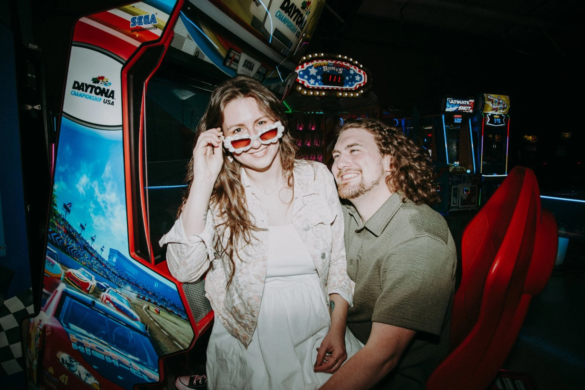 A couple sitting together at a racing game in an arcade