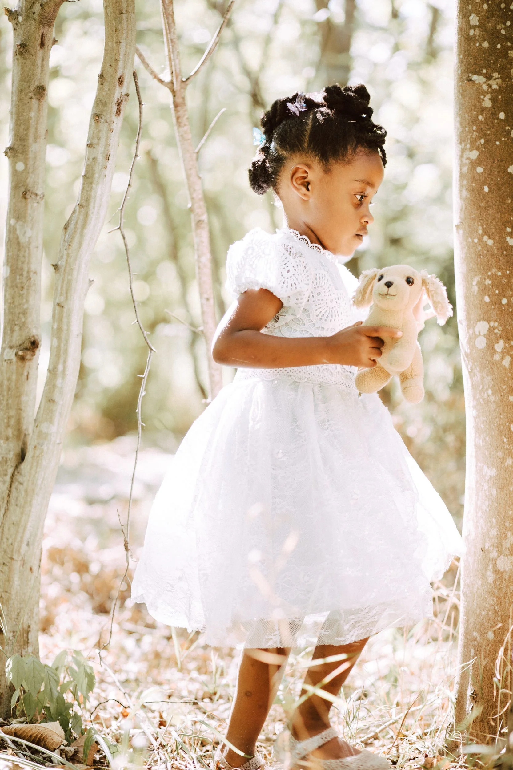 A small child in a dress holding a stuffed dog 