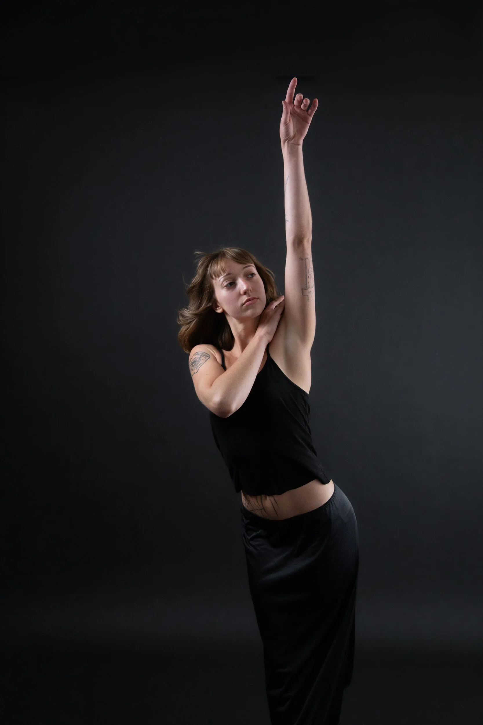 A person with one arm across their body and the other reaching up 