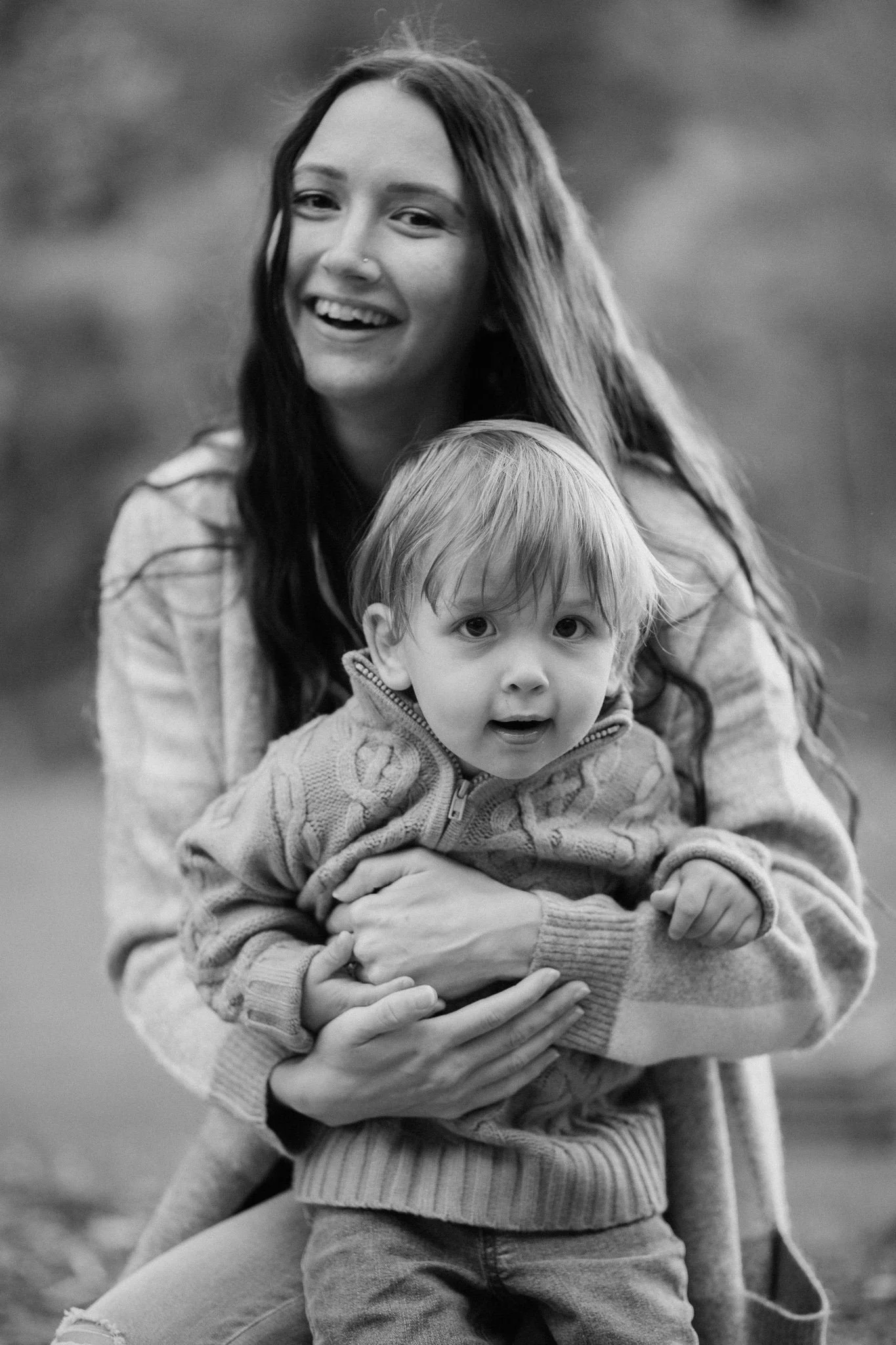 A parent smiling and holding their toddler 