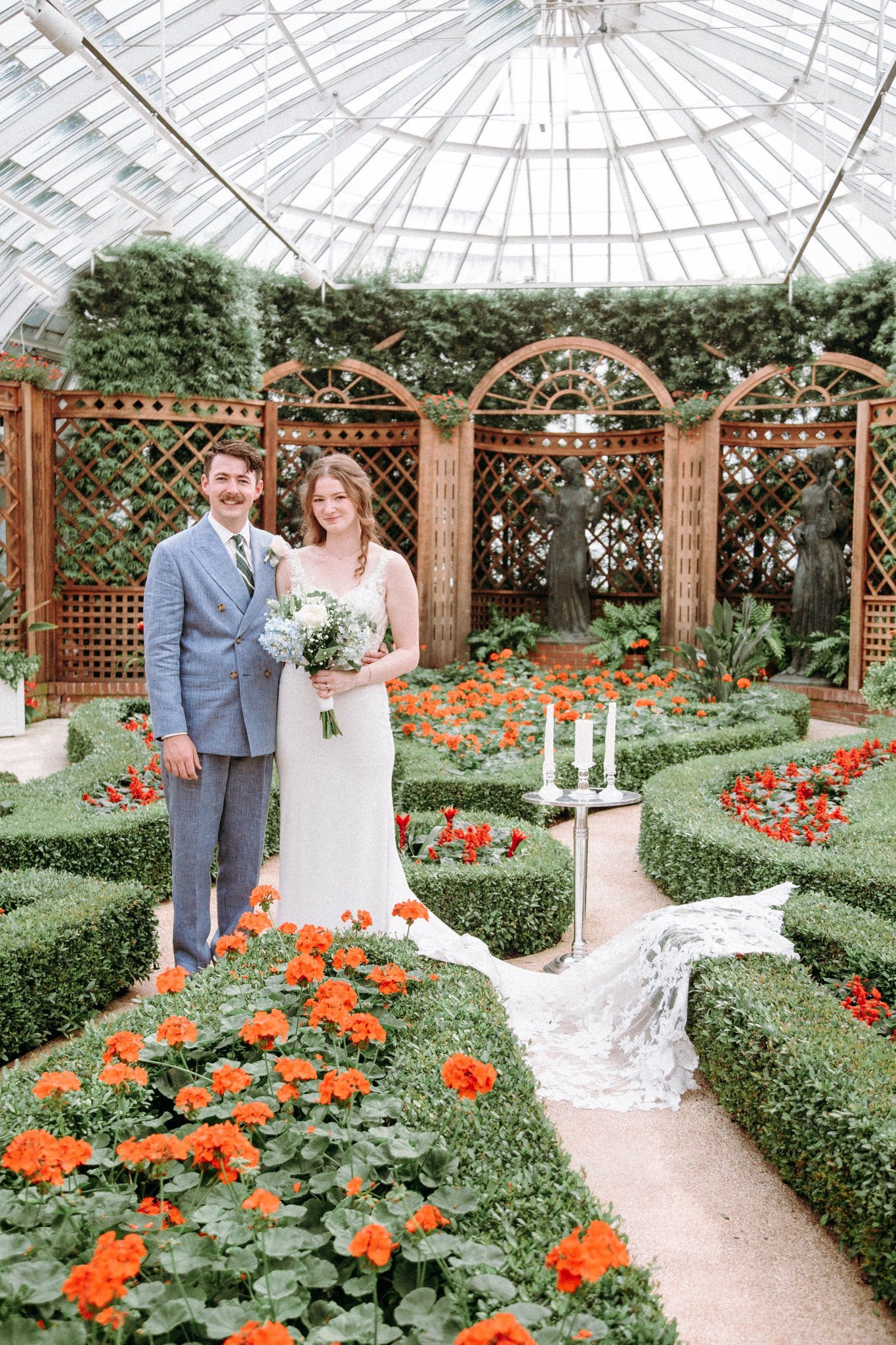 A newlywed couple standing in a small garden area