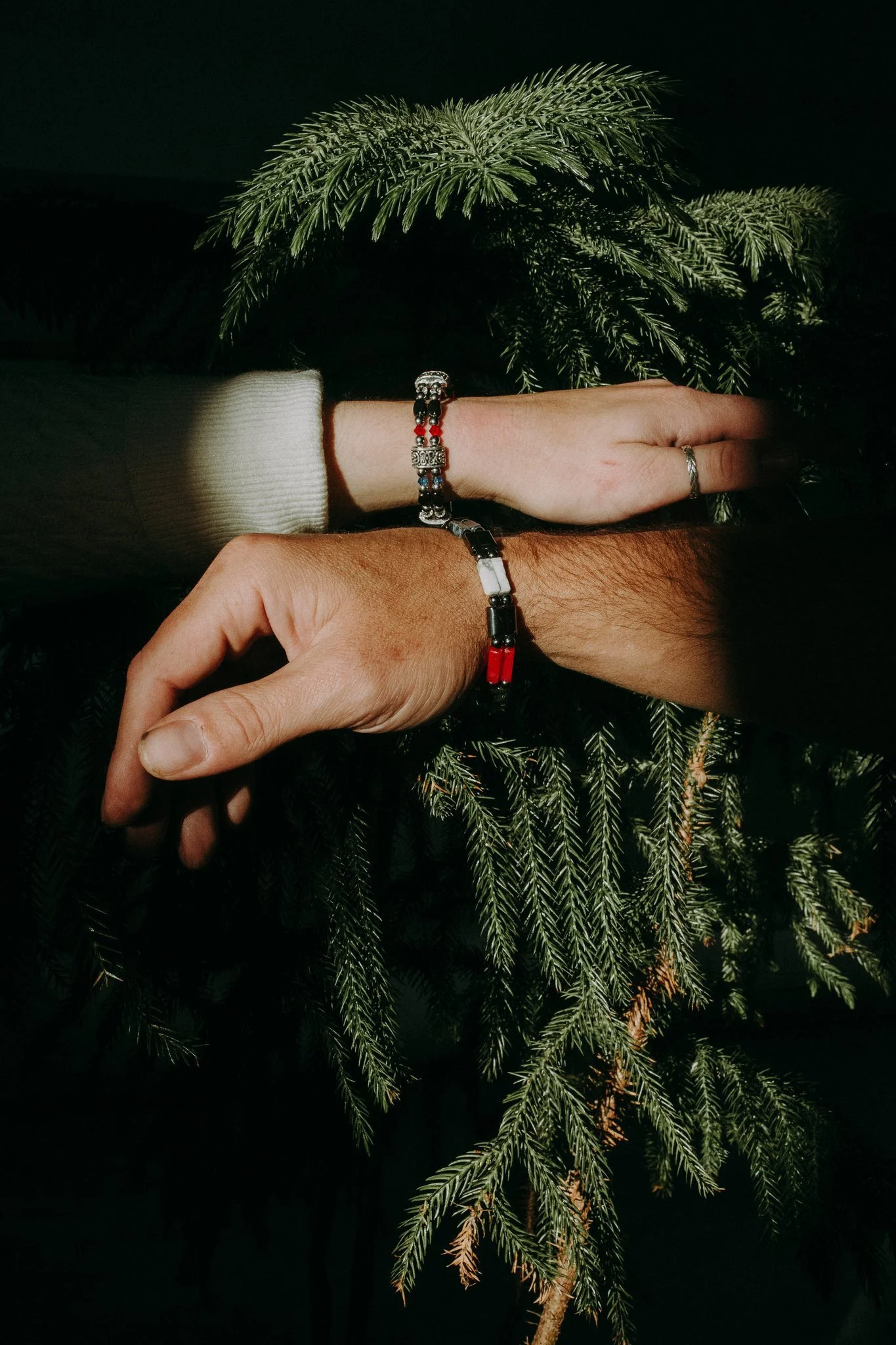 Two wrists showing off bracelets stacked on top of each other 