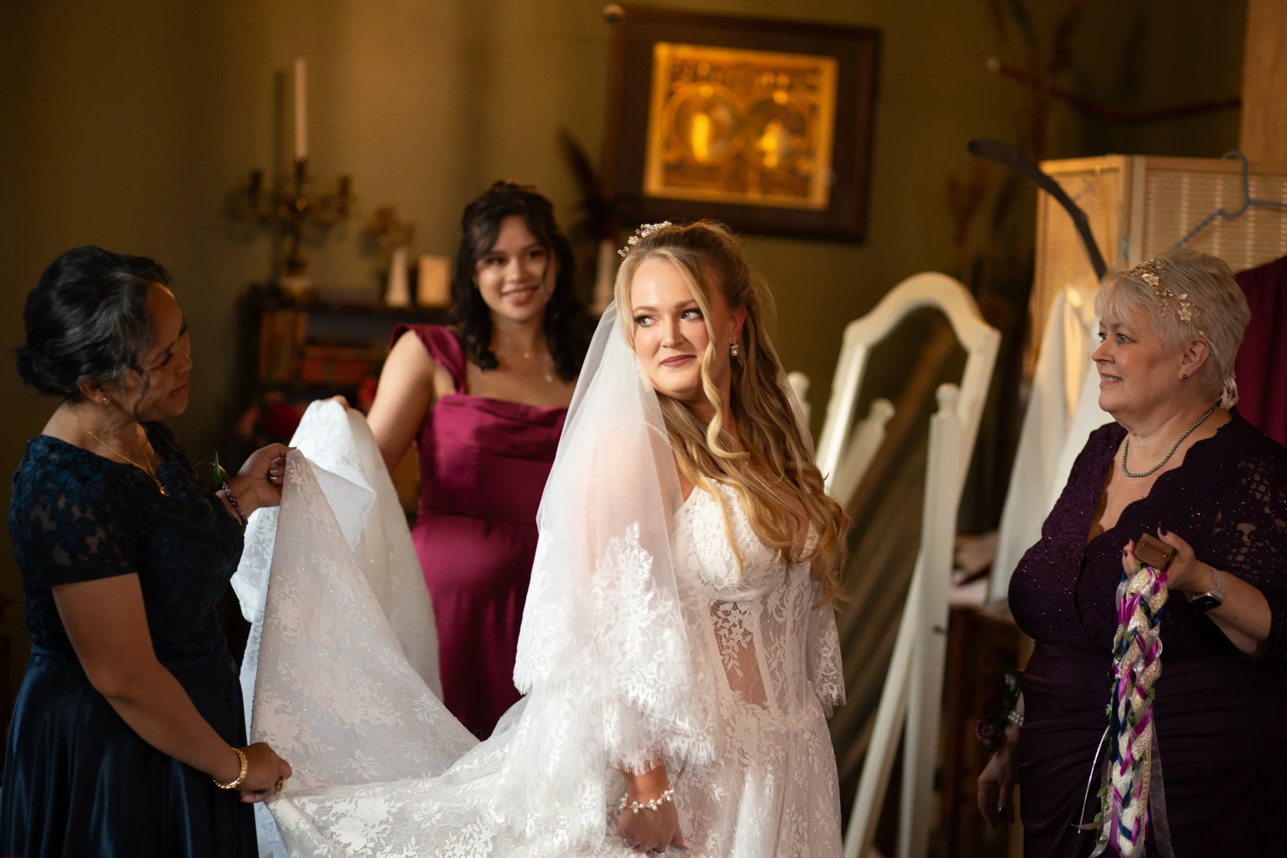People helping someone adjust the train of their wedding dress as they smile