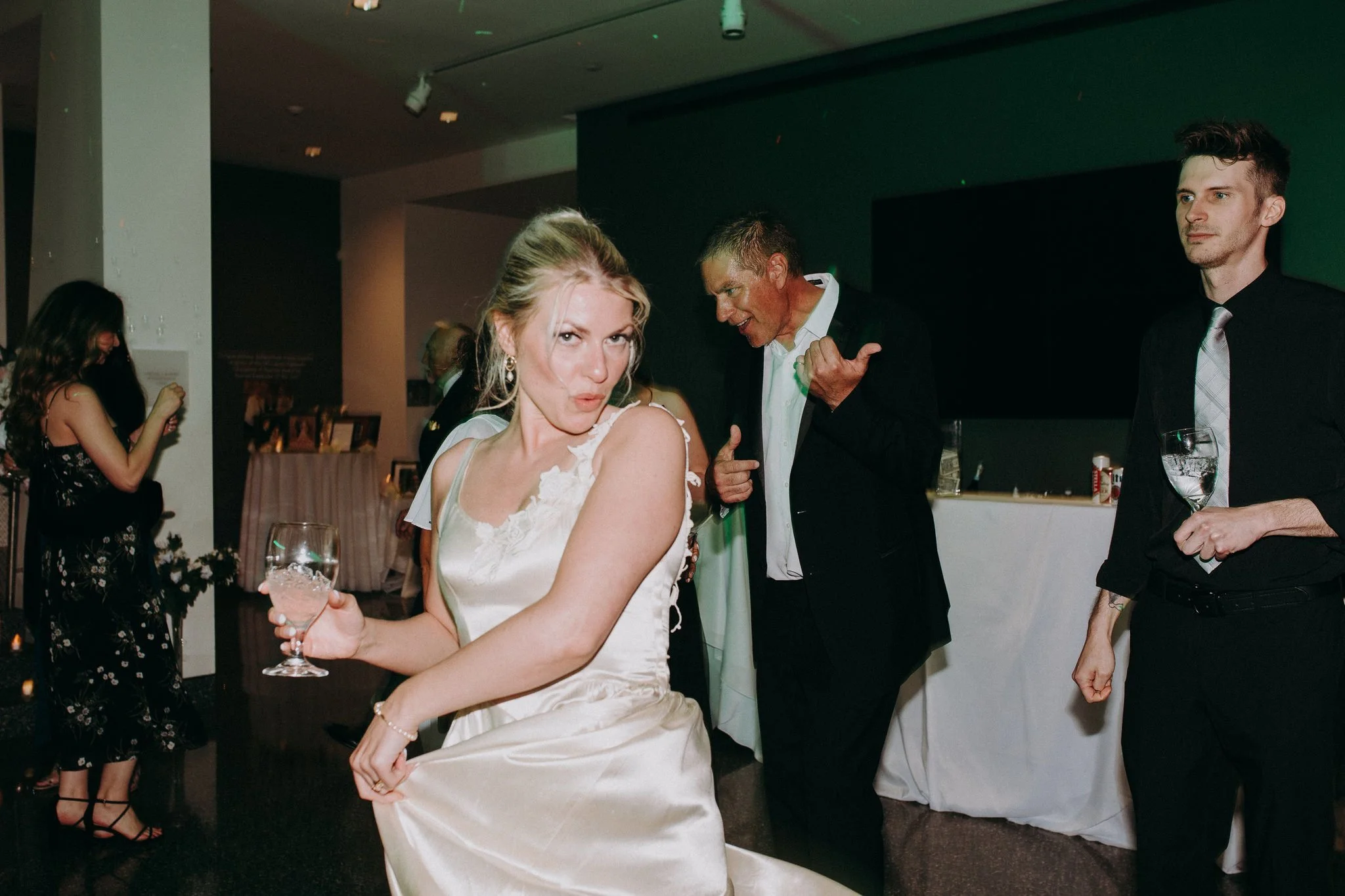 A newlywed dancing at their wedding reception while holding a drink