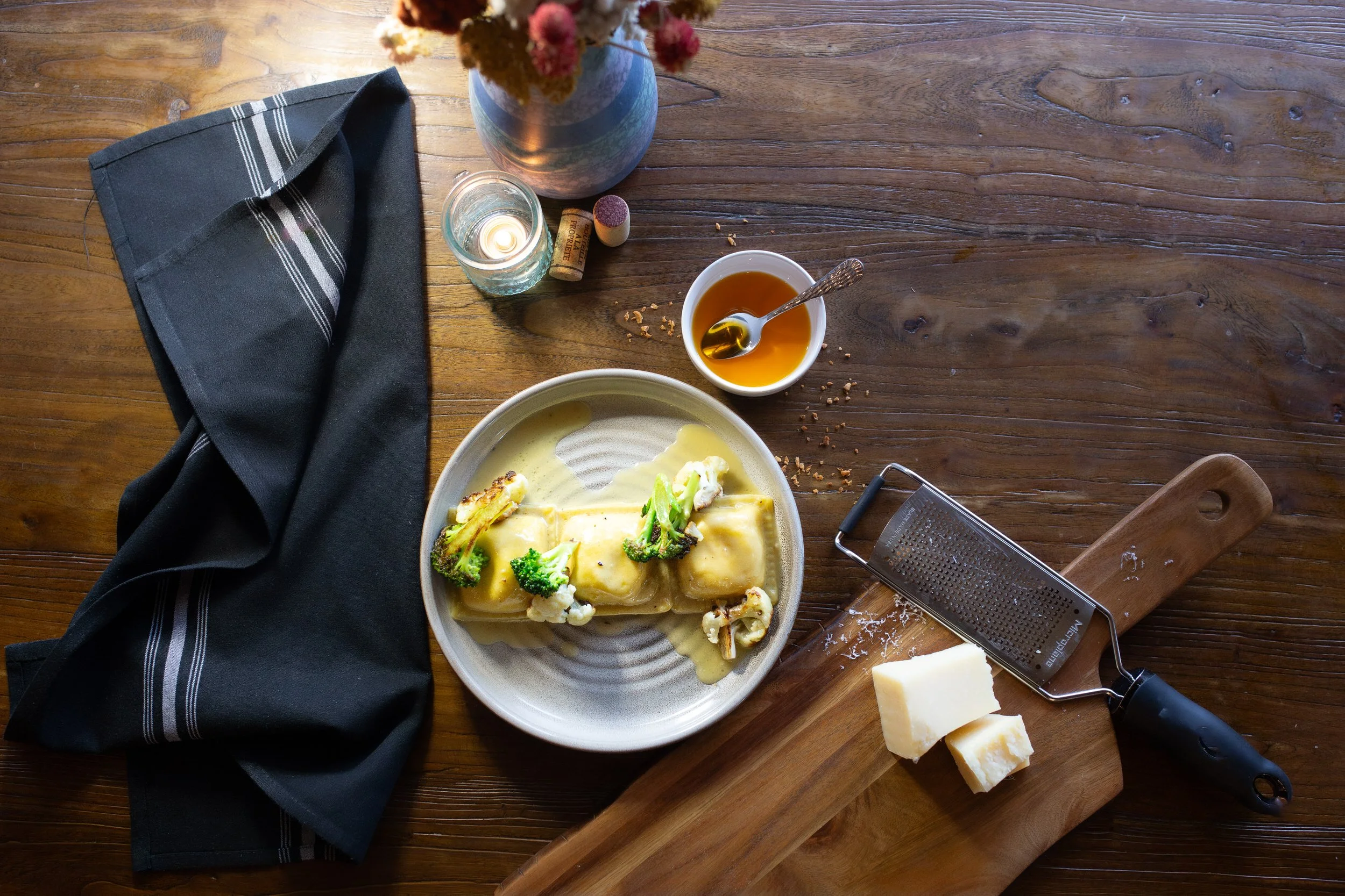 A table with a gourmet dish, sauce, cheese, and napkins on it