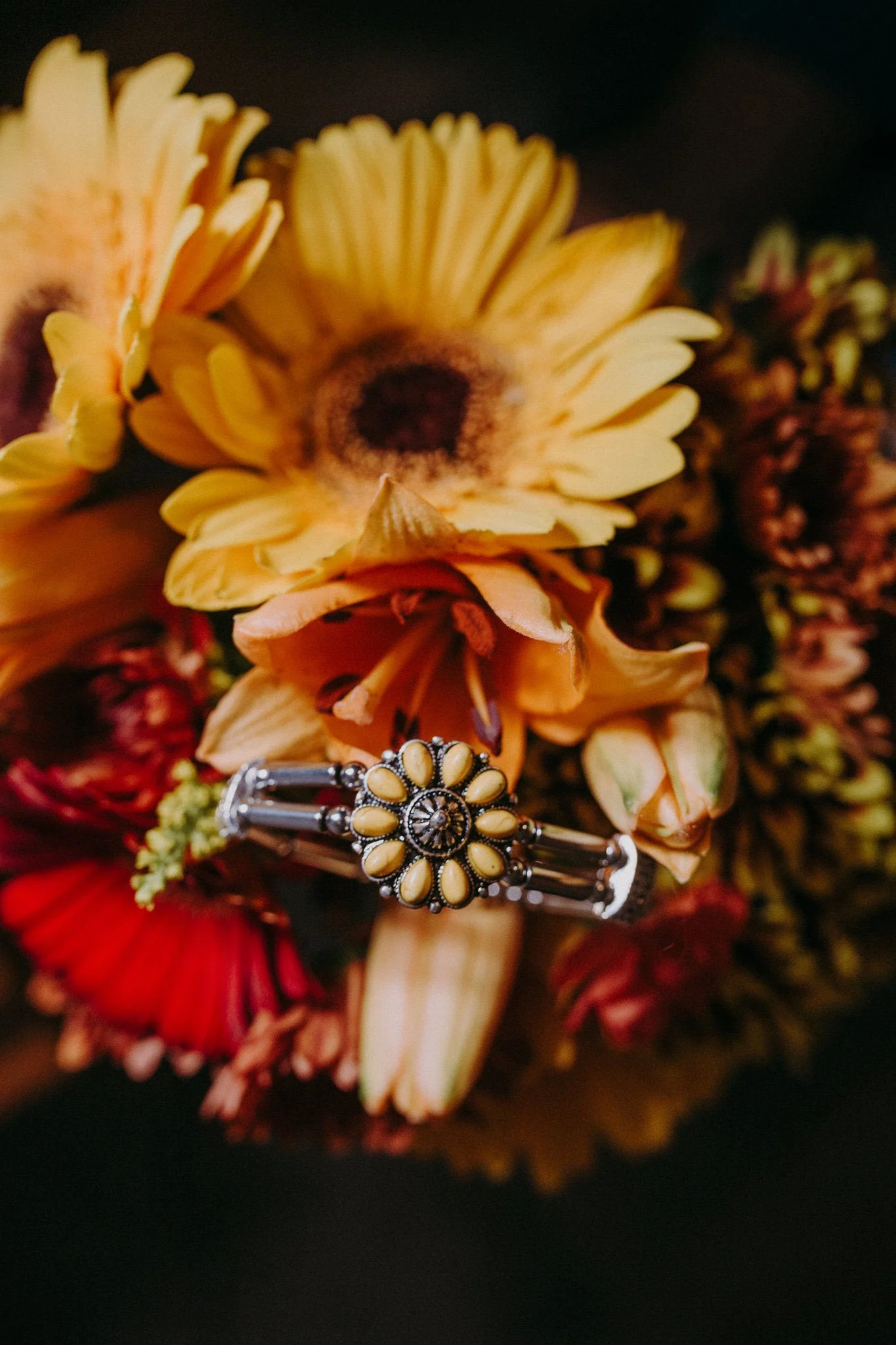 A piece of jewelry laid on top of colorful flowers 