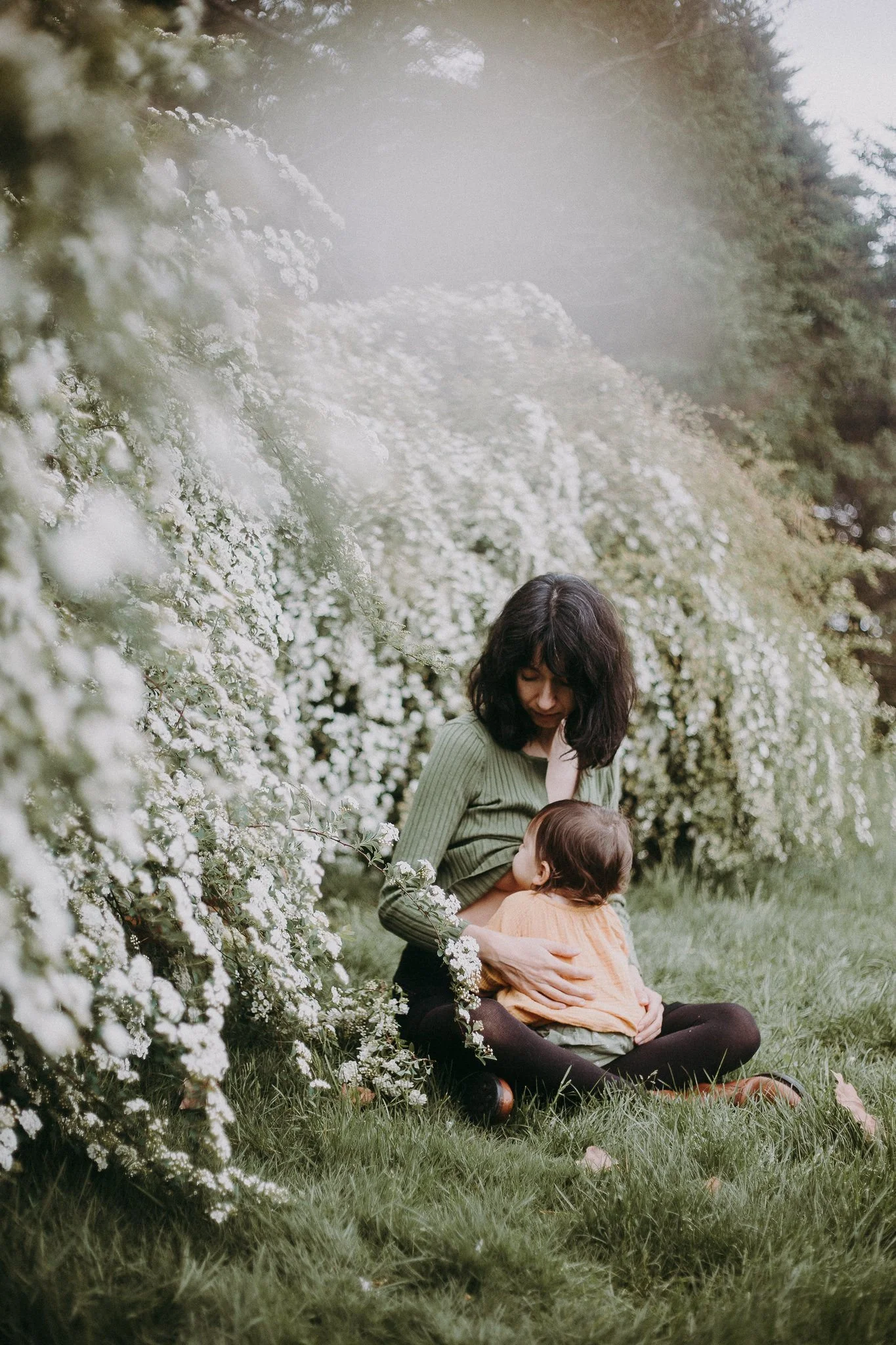 A person sitting on the ground breast feeding their child
