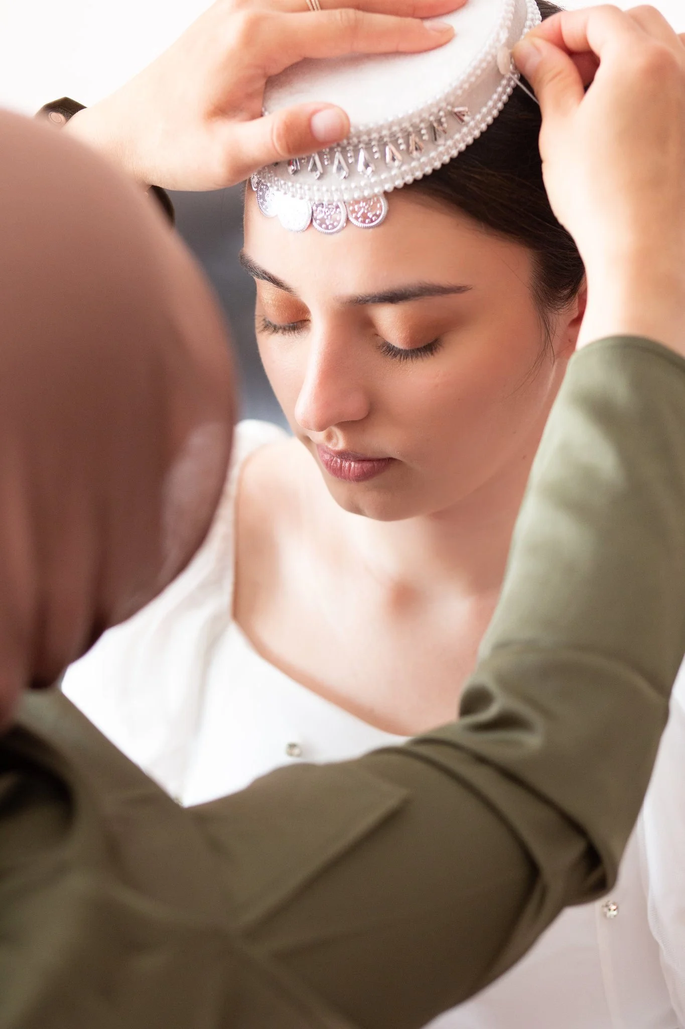 A person helping someone put on a veil on their wedding day