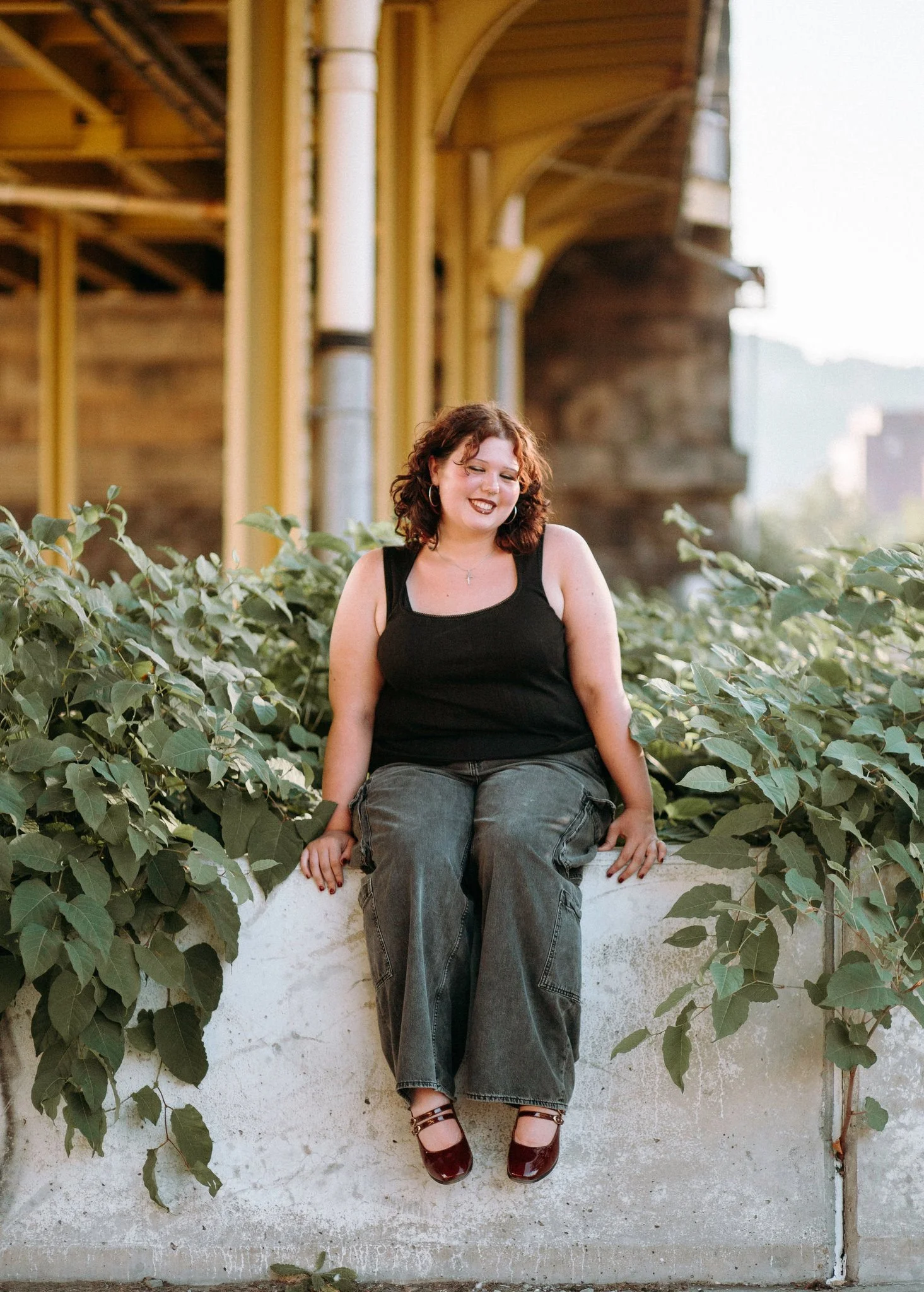 A person sitting on a small wall under a bridge 