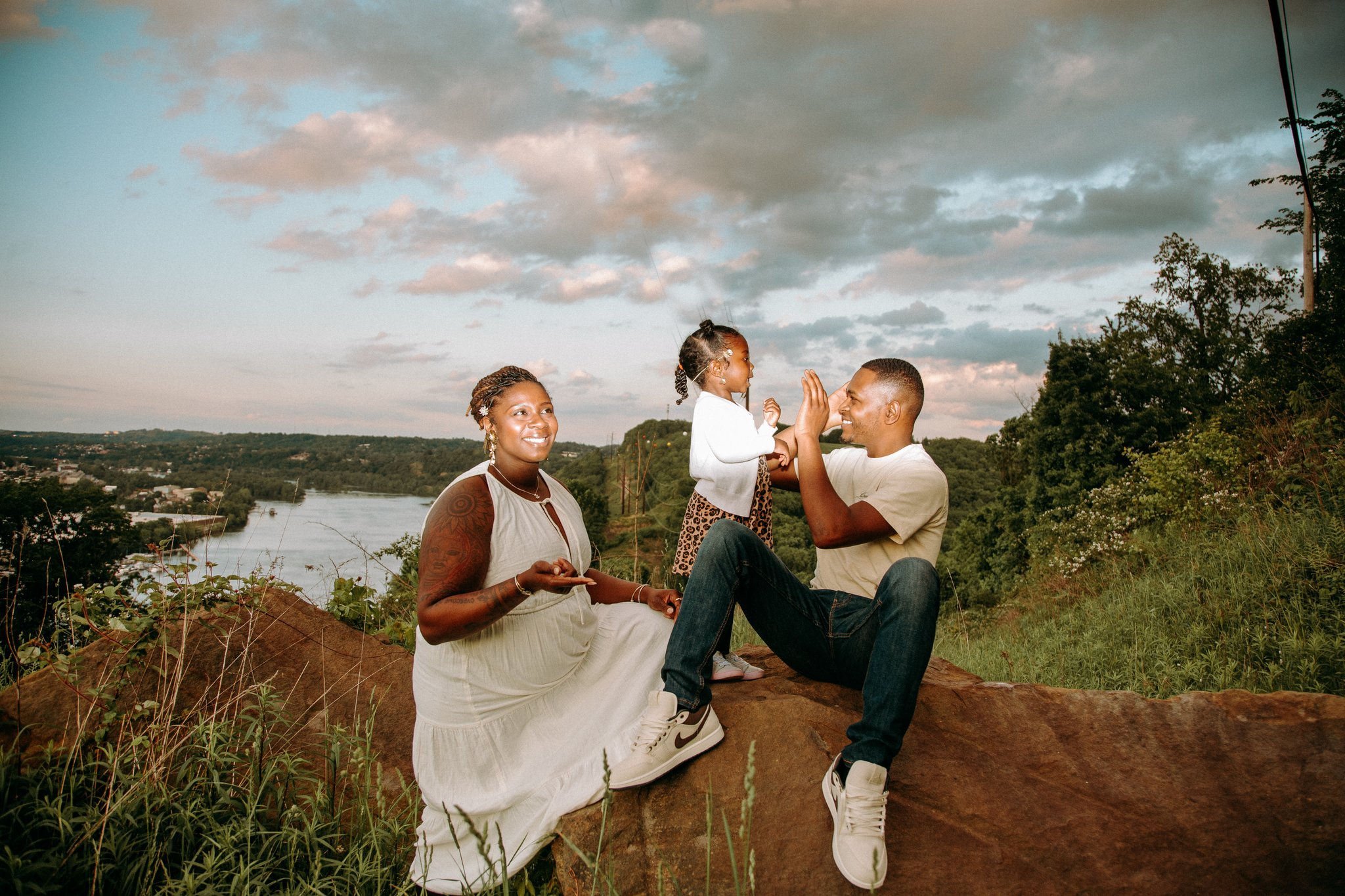 Two parents smiling and playing with their child in between them 