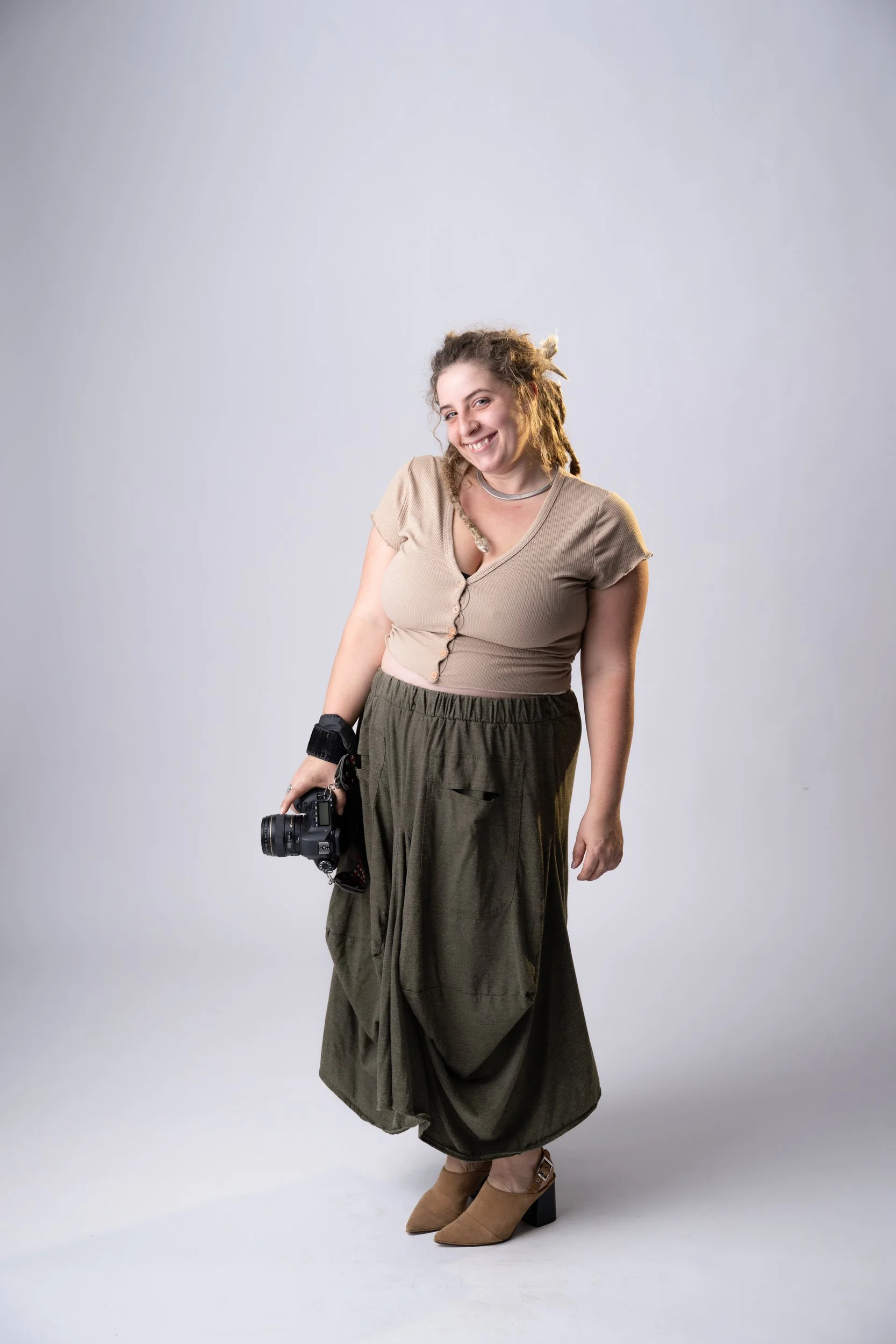 Tori Krout smiling while holding a camera with one hand down at her side