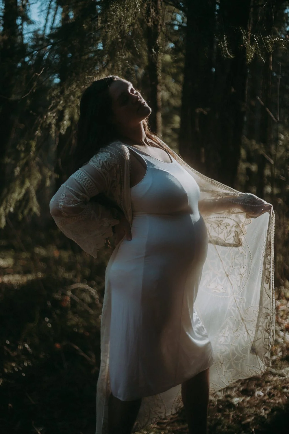A pregnant person with one arm holding out the end of a sweater 