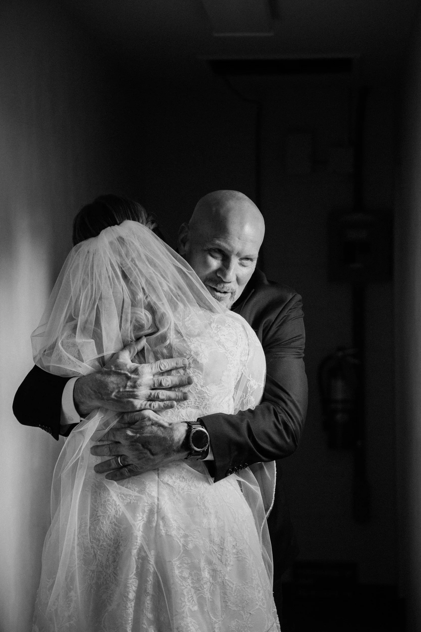 A parent hugging their child who is wearing a wedding dress