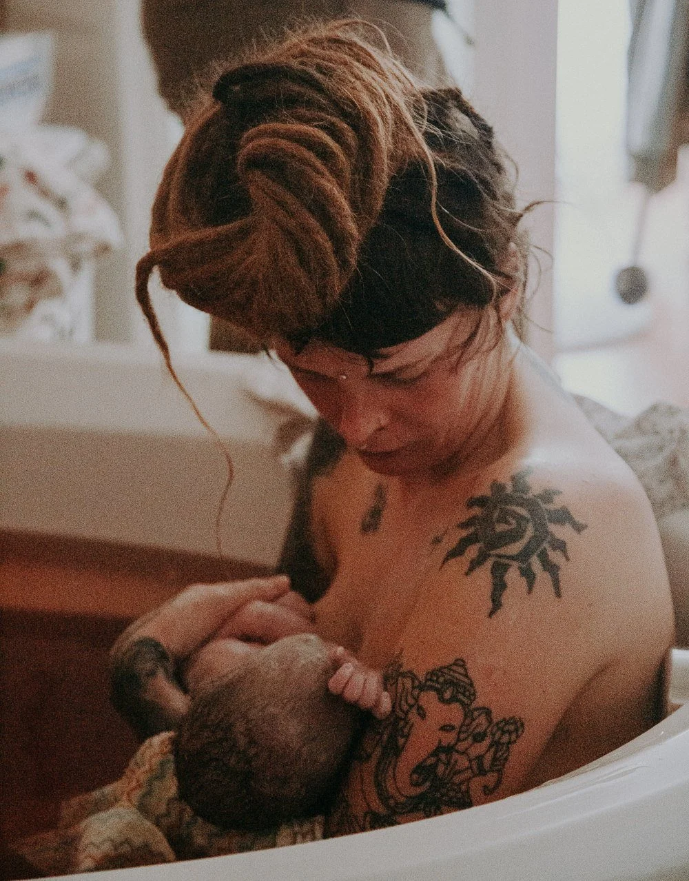 A mother sitting down cradling a newborn baby