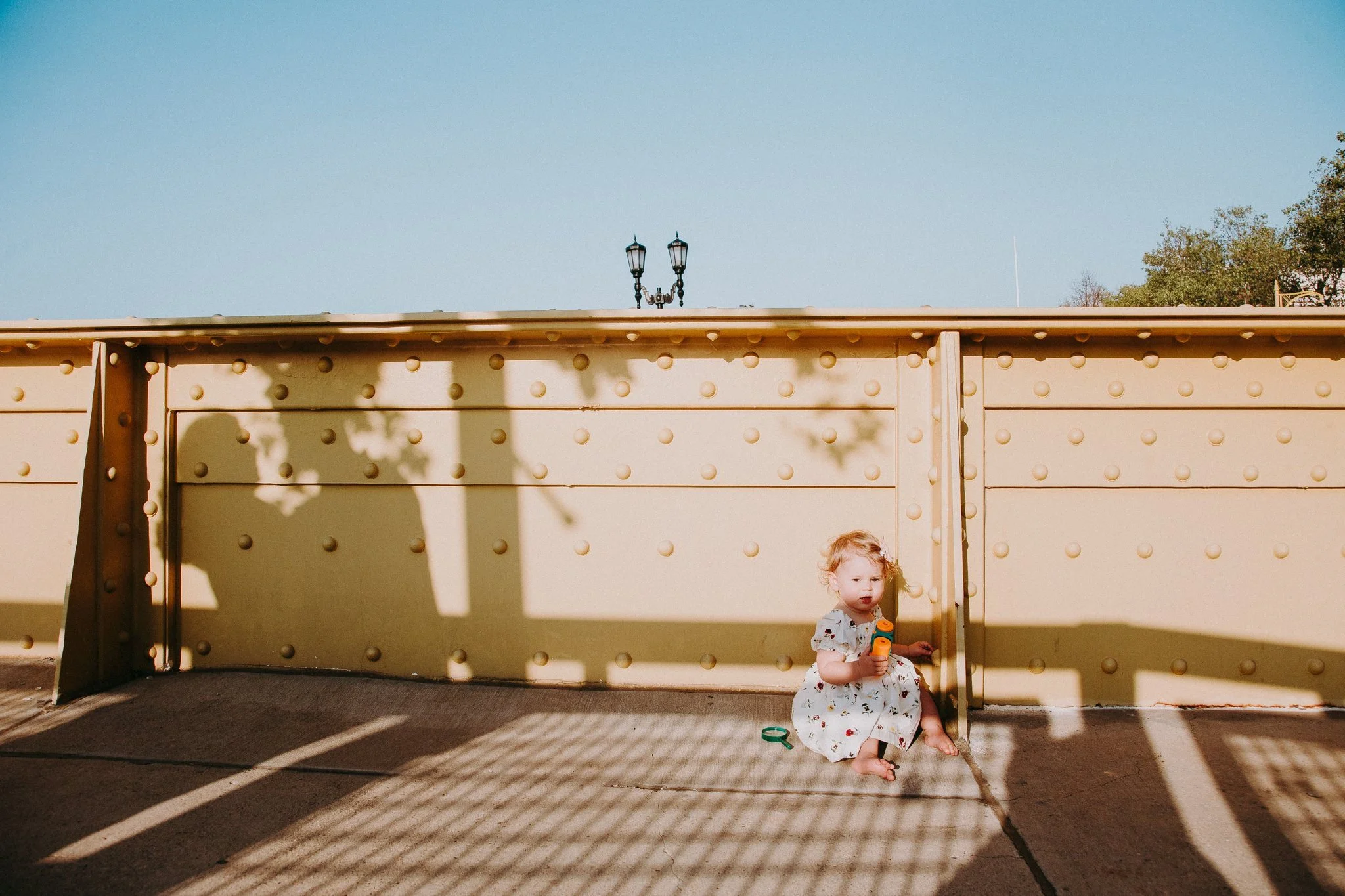 A small child sitting on an industrial bridge