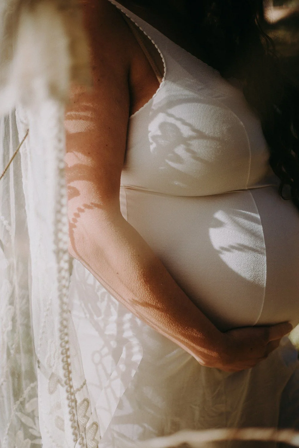 A close up of someone holding the bottom of their pregnant stomach 