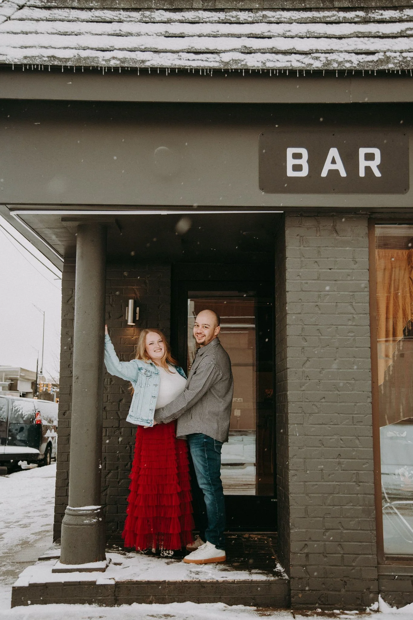 A couple smiling and standing close together at the entrance to a bar