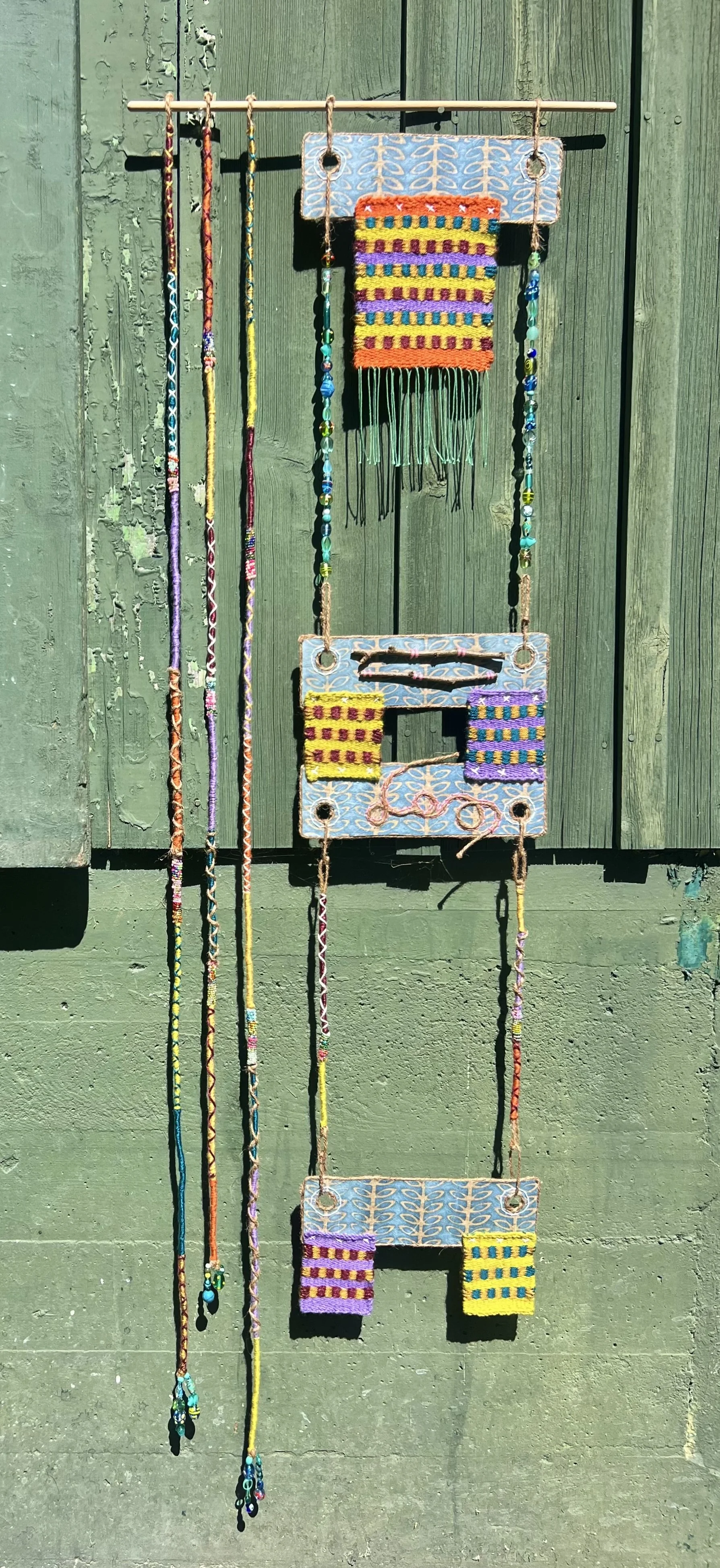 Untitled. Materials: cardboard, twine rope, found object, acrylic yarn, embroidery floss. 14in x .5in x 48in. Year created: 2025