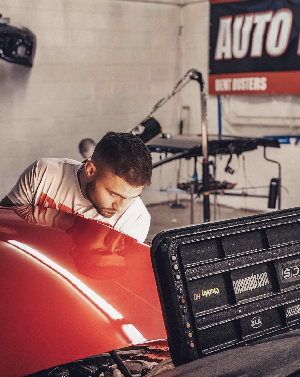 Dent Busters technician performing paintless dent repair auto hail repair on a hail-damaged vehicle