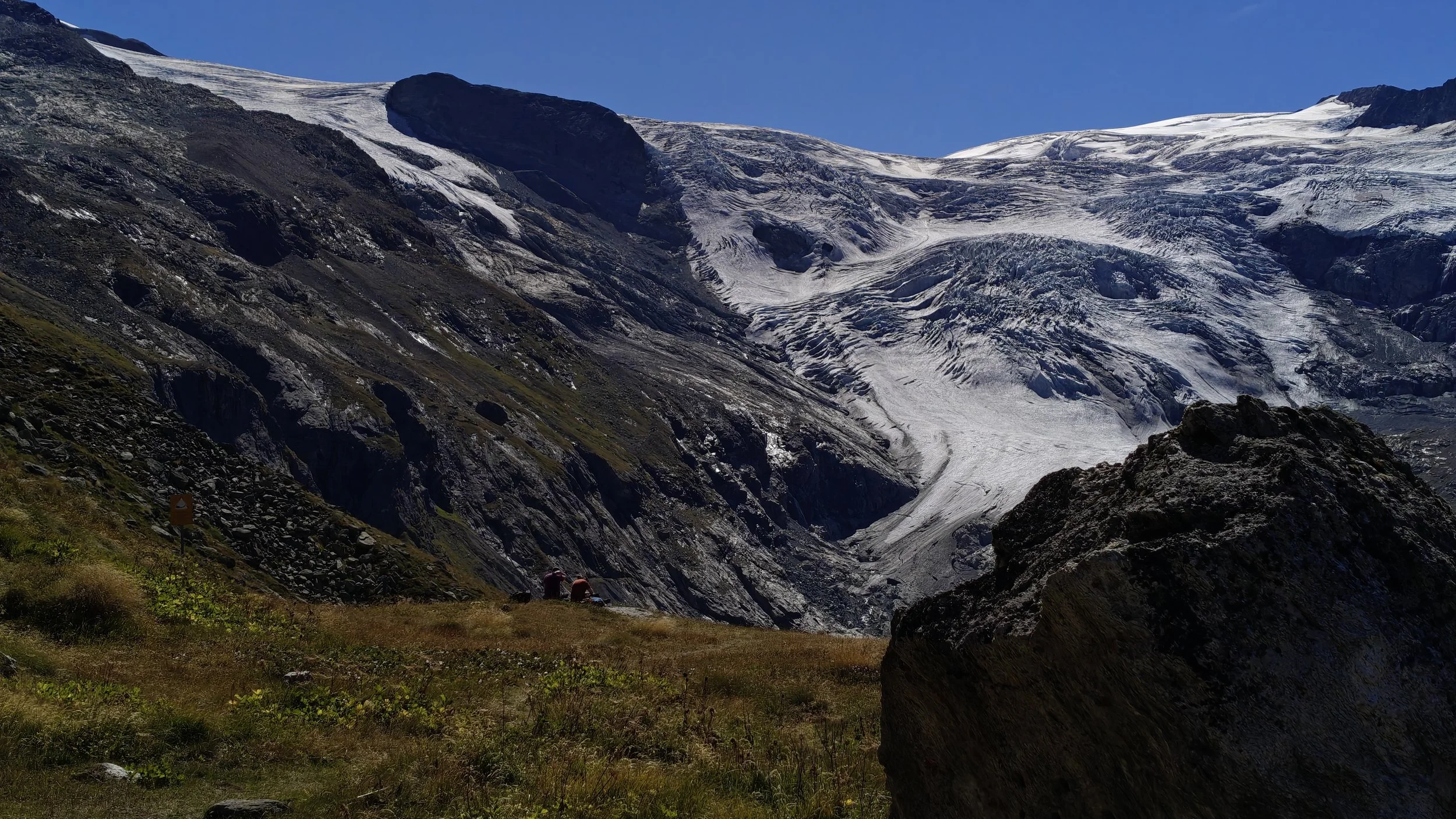 Two people watching the last traces of the glacier
