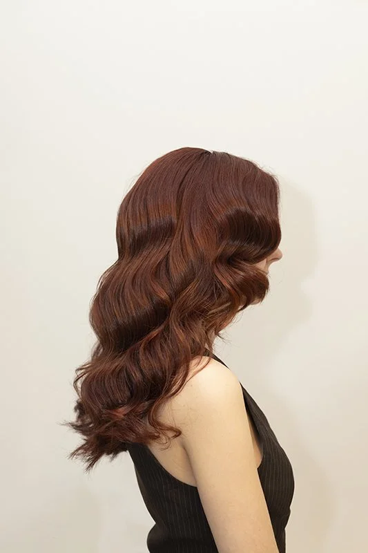 Mujer con cabello largo y rizado de color castaño rojizo