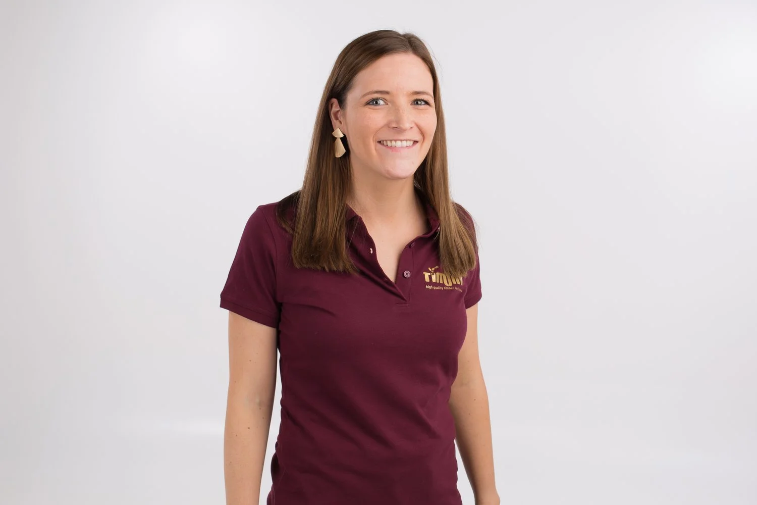 Lieselotte, order intake en purchase in een bordeauxkleurig polo, lachend voor een witte achtergrond.