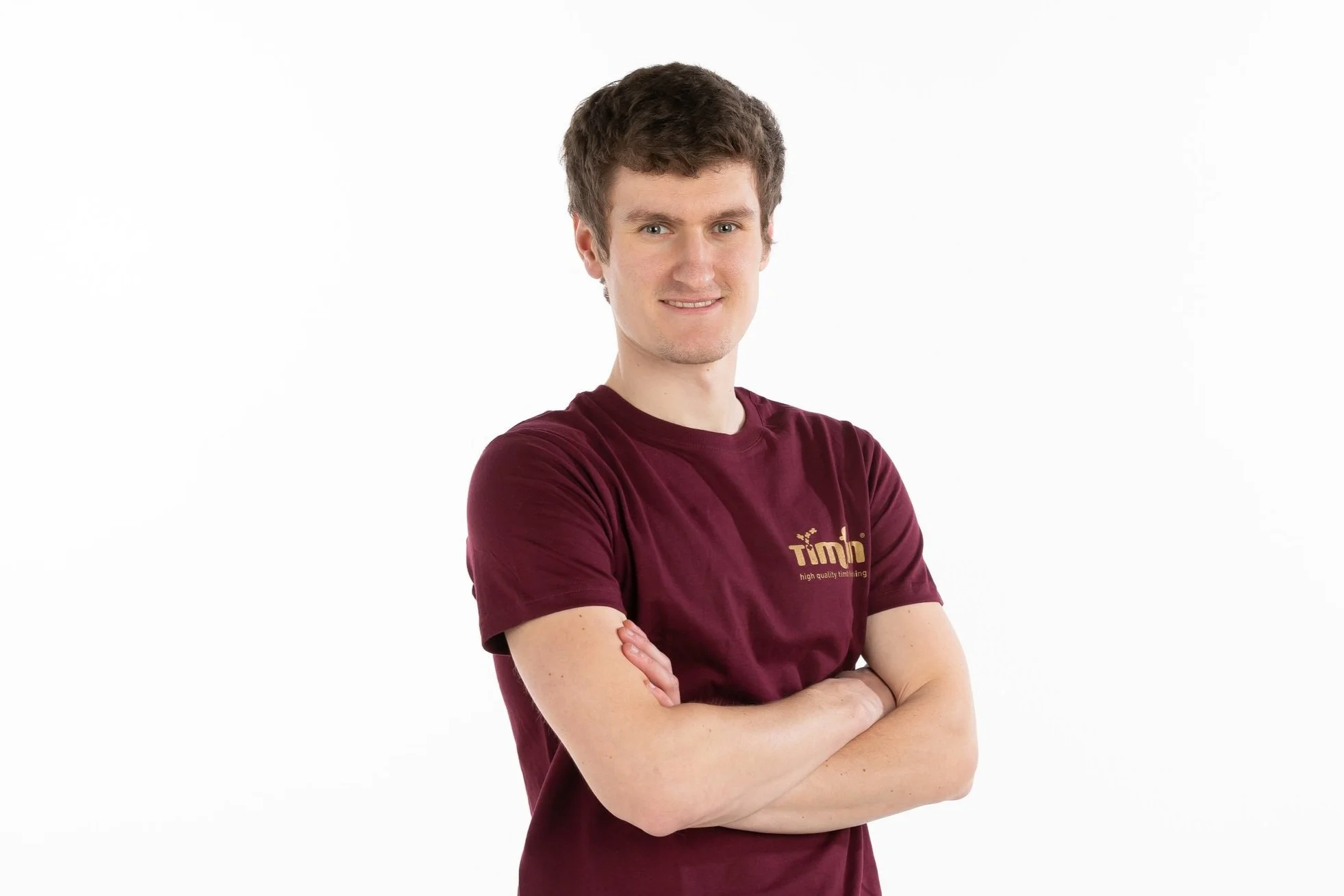 Niels, onze projectleider voor on-site gevel en terras onderhoud met het logo 'timfin' en de tekst 'high quality wood finishing', staat met gekruiste armen voor een witte achtergrond.