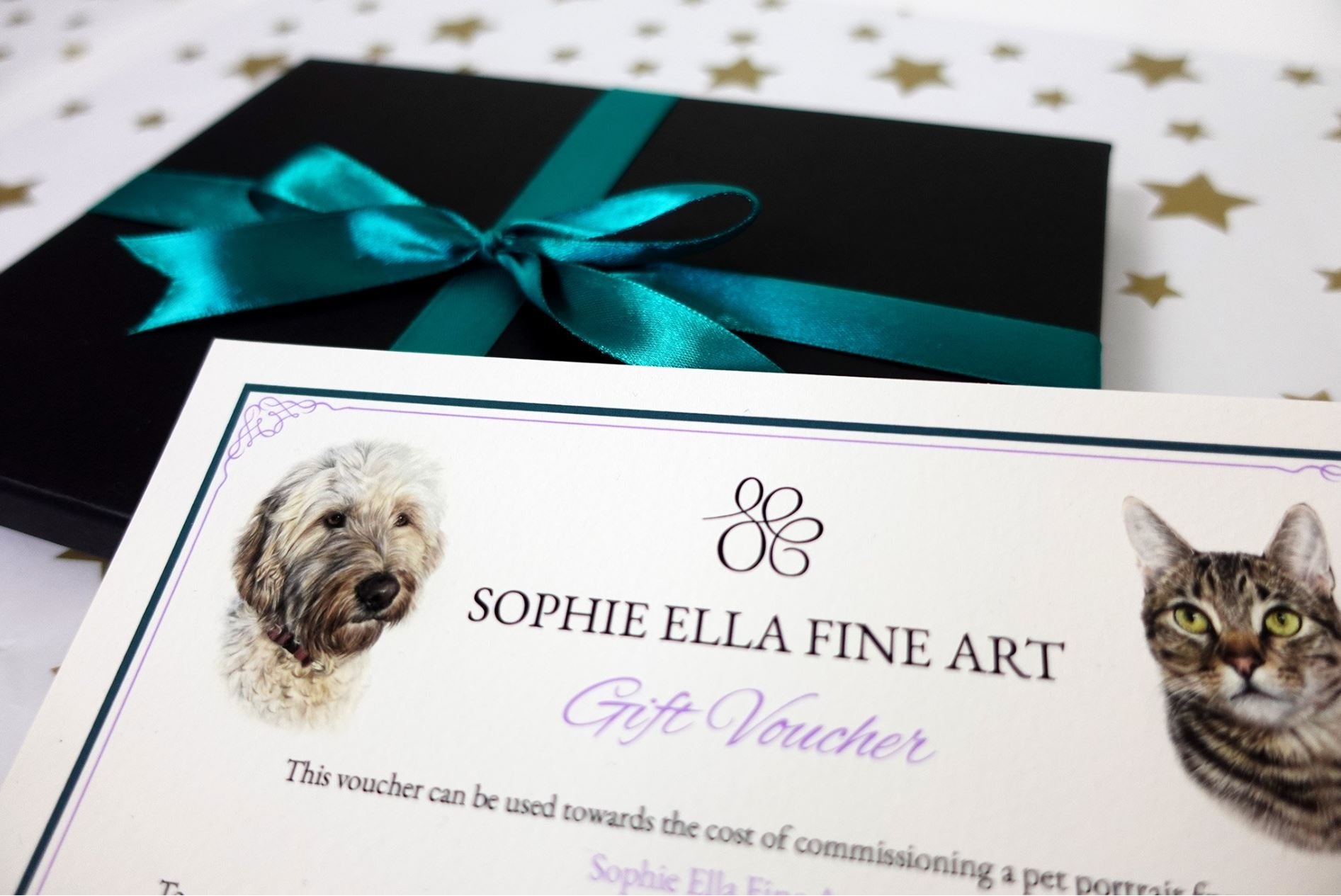 A pet portrait gift voucher on a presentation box tied up with green ribbon