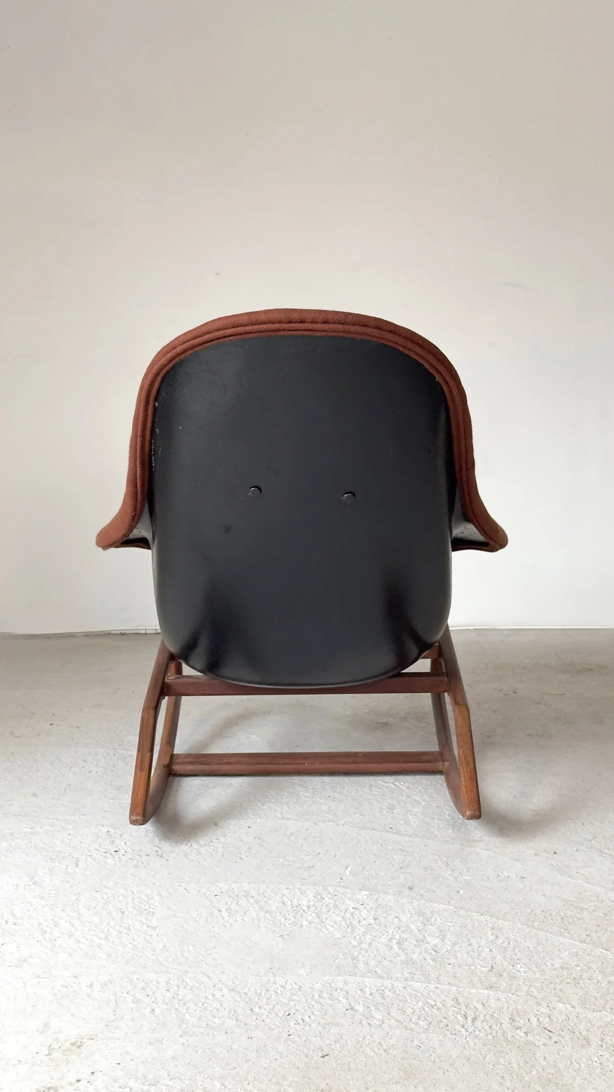 Rear view of Gemini Rocking Chair showing black fibreglass shell and afromosia base