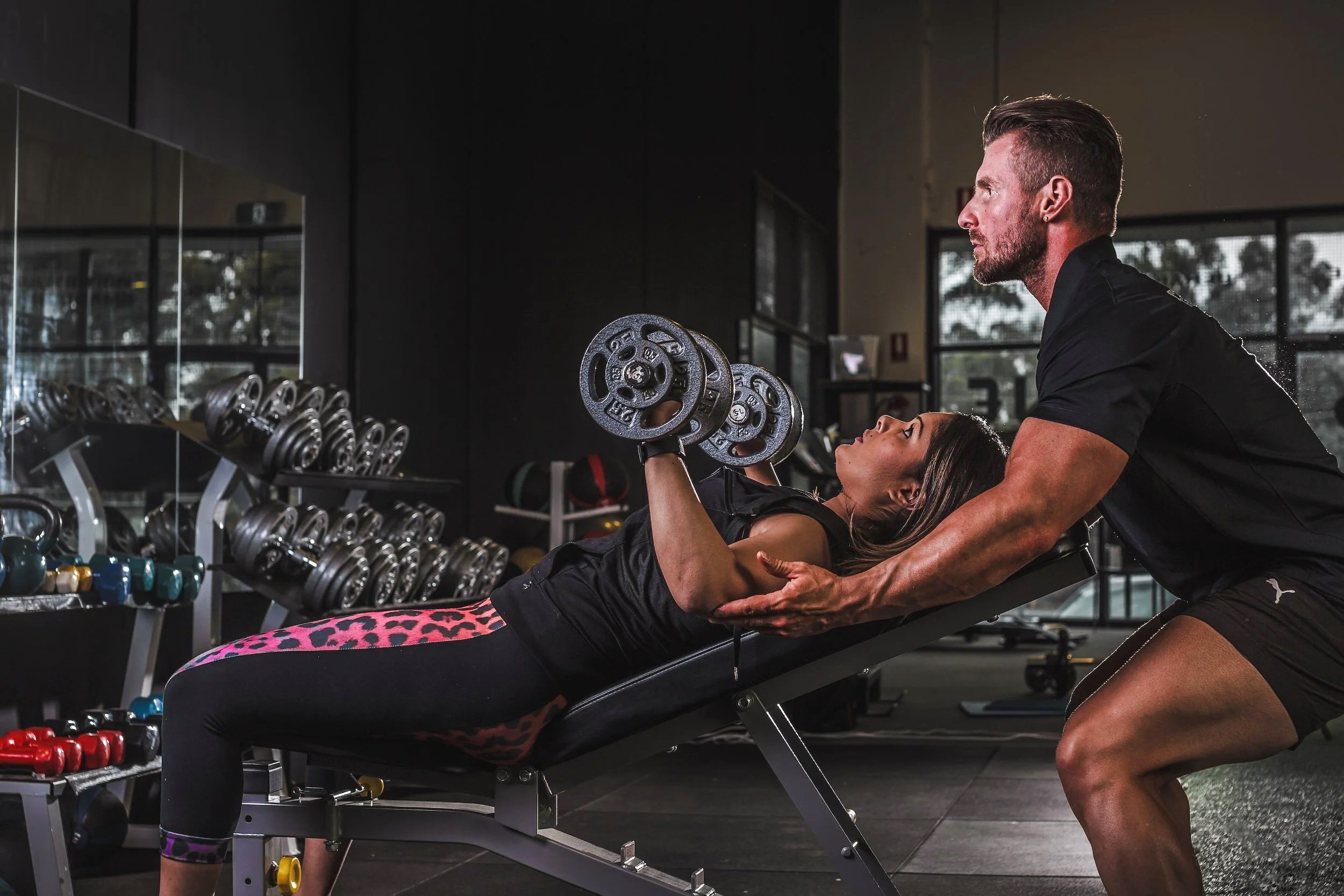 Personal Trainer spotting a client in the gym with correct form