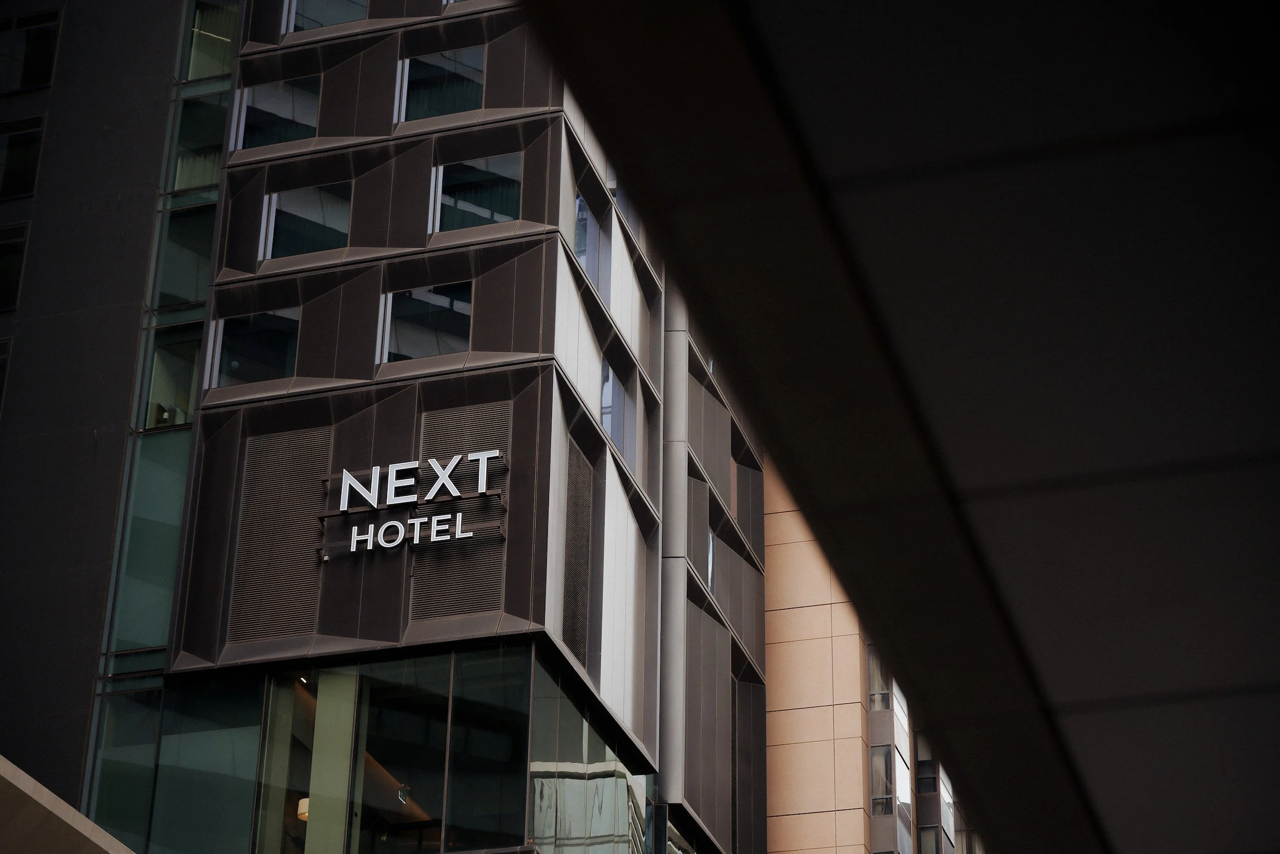 Detail close up shot of the sign out the front of the Next Hotel Curio by Hilton Melbourne