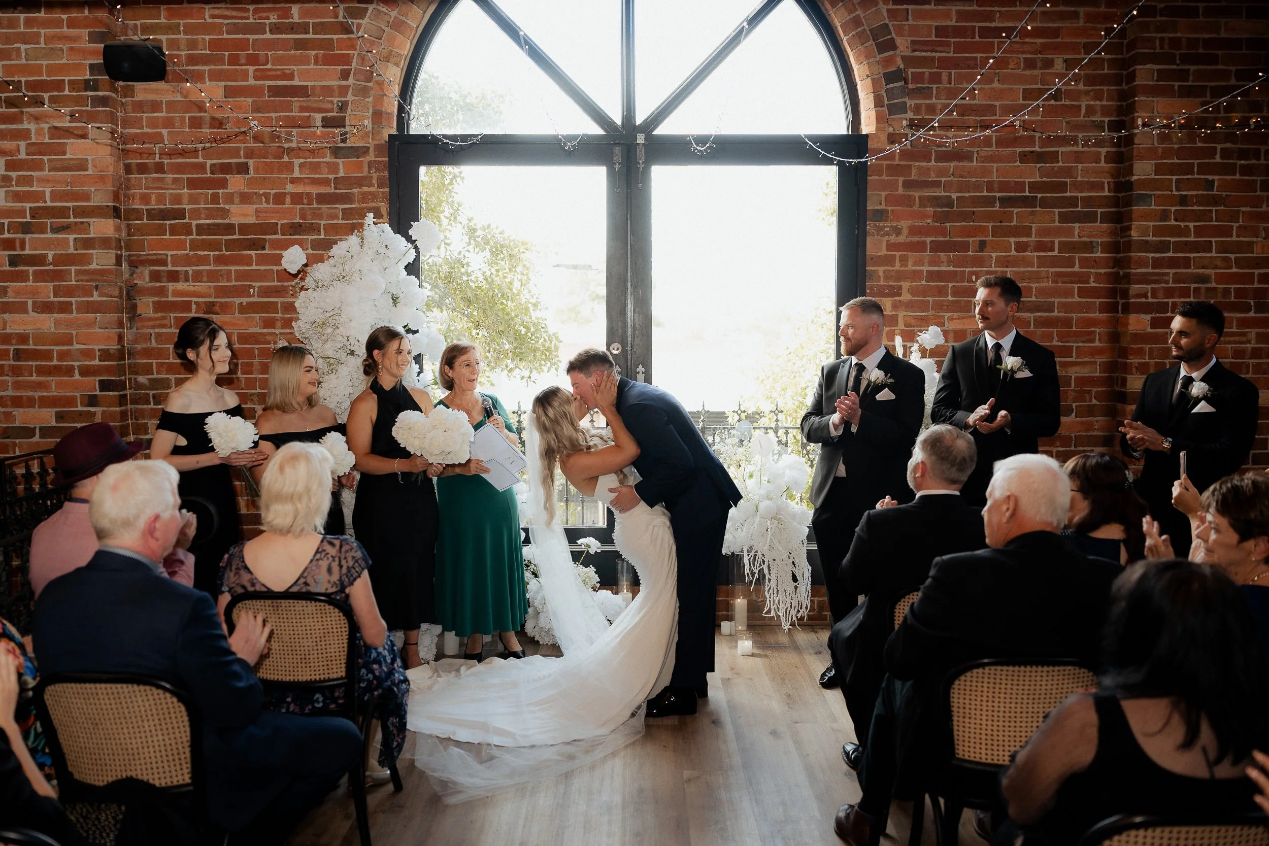 Couple sharing their first kiss under the grand window of Chapel 1885 Collingwood