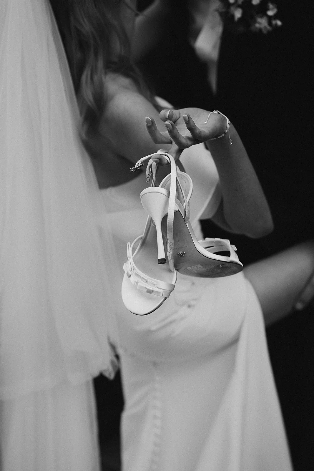 Cheeky sexy photo of bride holding her shoes while she kisses her groom