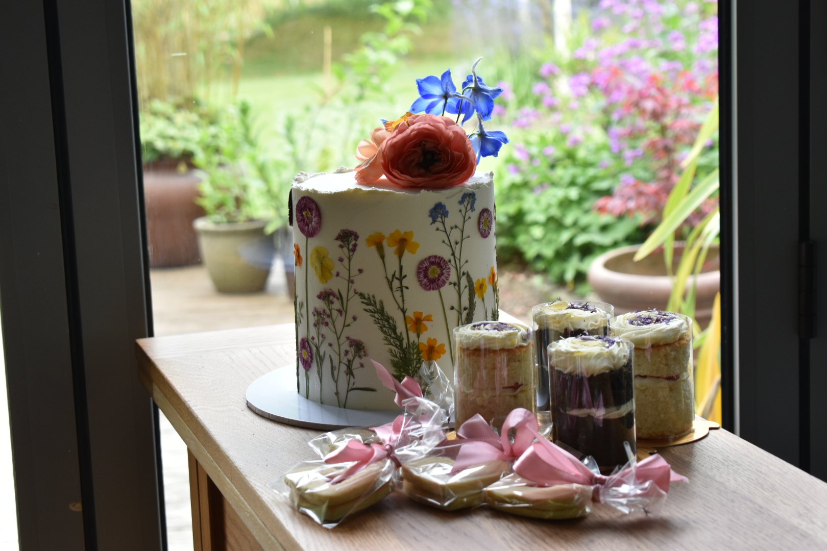 Elopement wedding cake finished with pressed edible flowers, mini-cakes and favour biscuits.