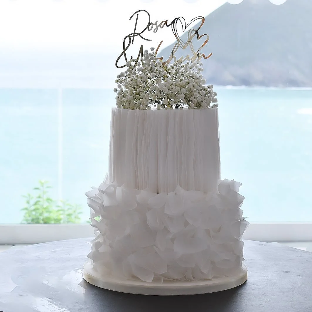 🤍 Rosa knew exactly what she wanted: classic, romantic, unforgettable&hellip; 

This elegant two-tier design was all about timeless style &mdash; smooth white fondant, delicate wafer paper ruffles, fresh gyp, and a gold personalised topper that caug