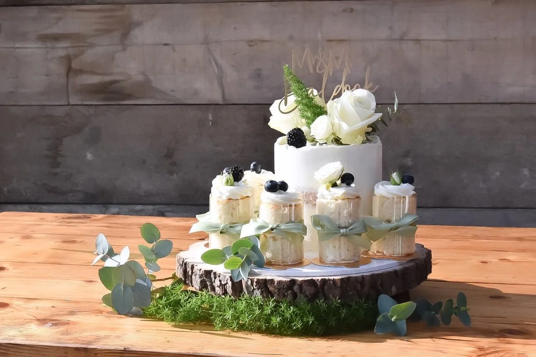 A soft, romantic design created for a beautiful celebration at sunny Tree Top Escape, Devon 🤍☀️

This elegant semi-naked cake was finished with delicate white roses, fresh foliage, and seasonal berries, paired with individual mini cakes, each one ca