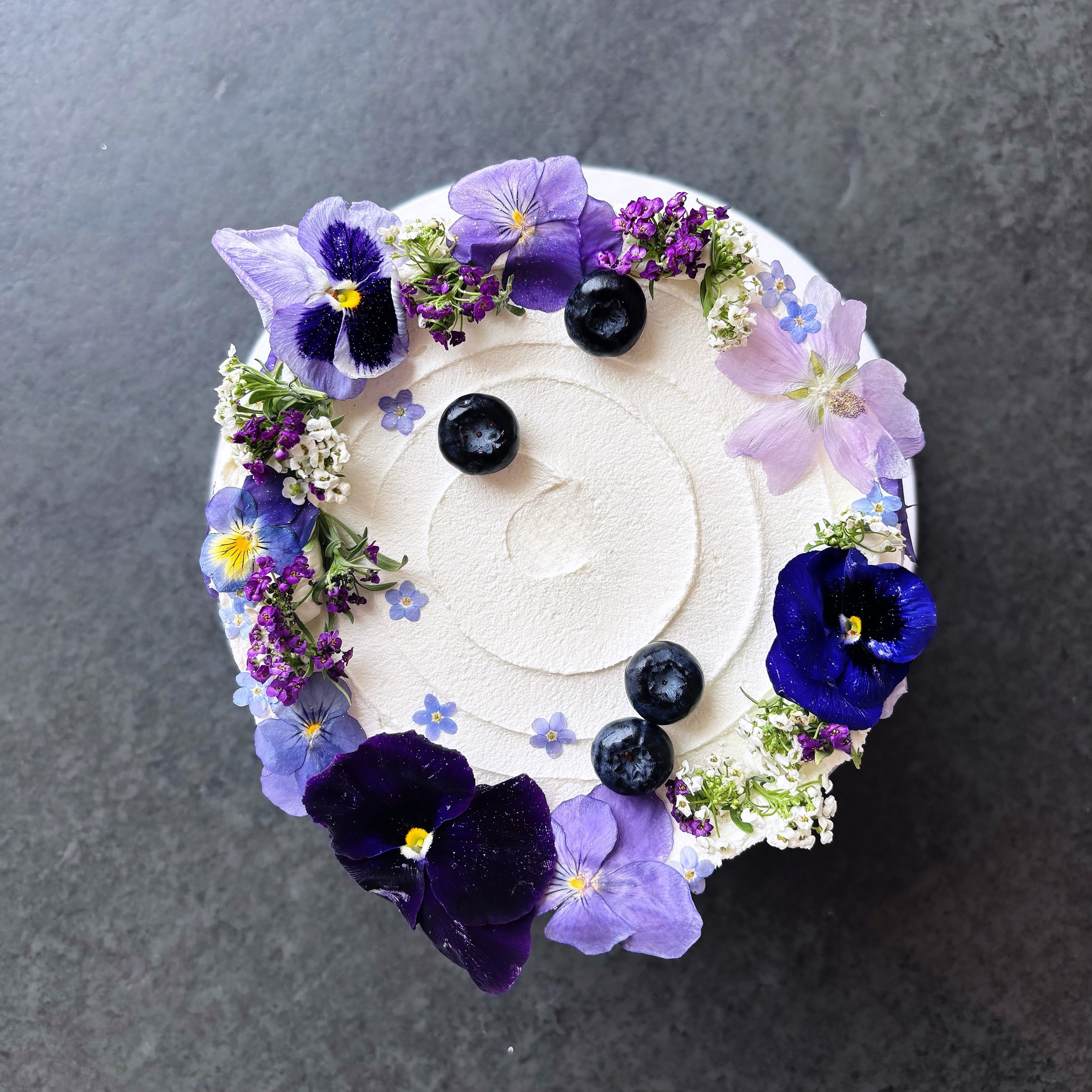Delivered yesterday to the beautiful Sandy Cove, this delicate single-tier cake was finished with a wildflower crown of edible flowers, fresh blueberries and the prettiest shades of violet, lilac and deep purple💜 Bride Millie knew exactly what she w