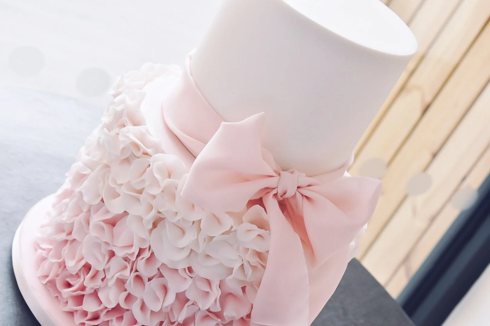 Pale pink ombre ruffle cake finished with pale pink silk bow.