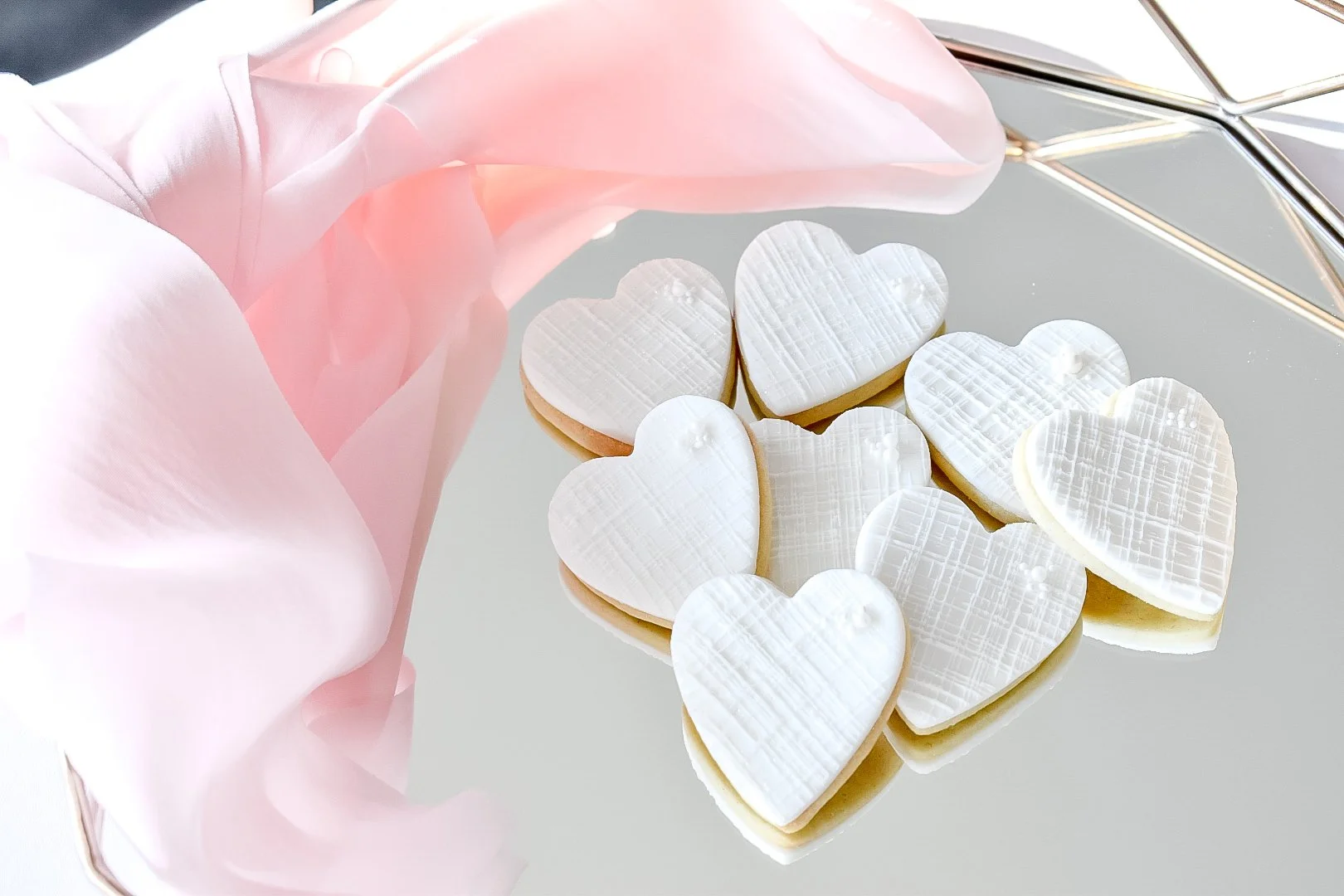 Heart-shaped wedding favour biscuits on a mirrored tray in Devon.