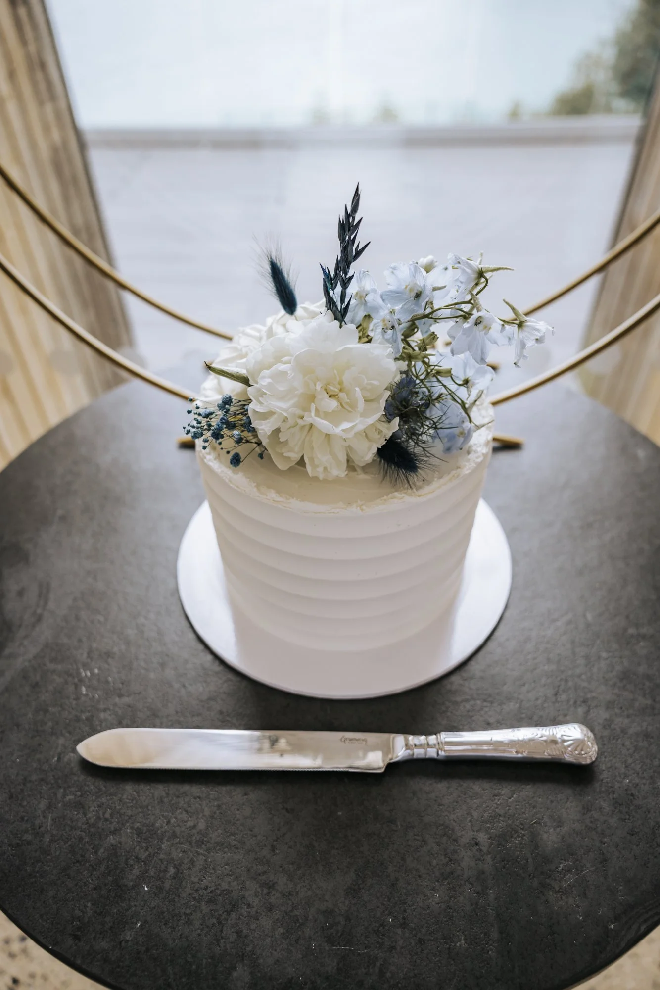 Modern white ridged buttercream wedding cake with white and blue florals
