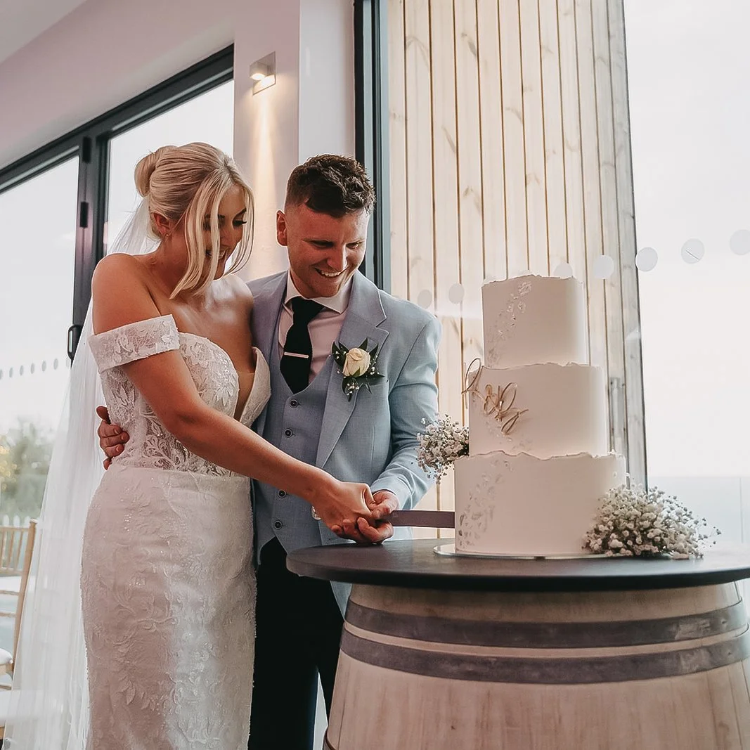 Bride and groom cutting their wedding cake at Devon coastal venue.