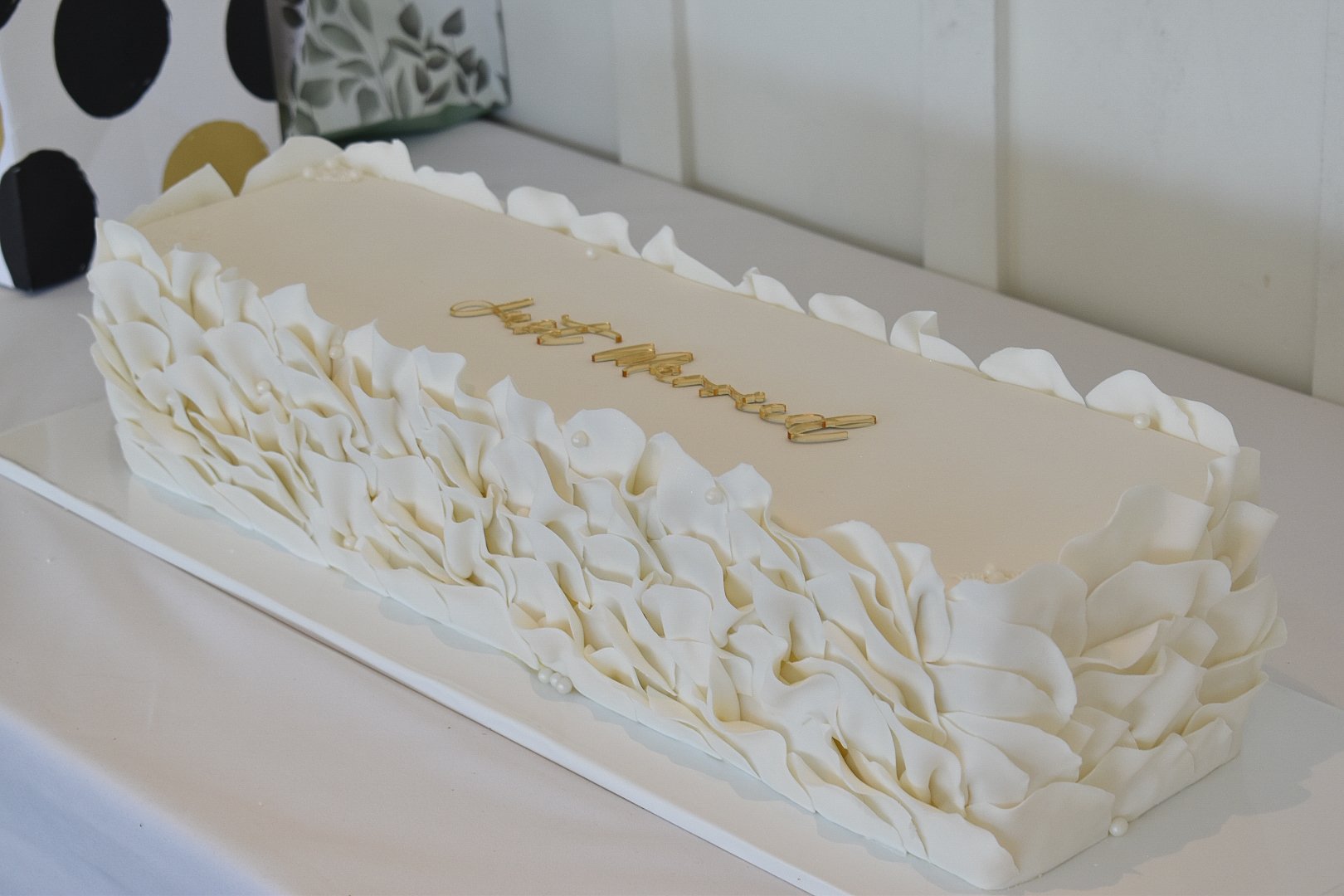 Long rectangular wedding cake with fresh flowers and fruit.
