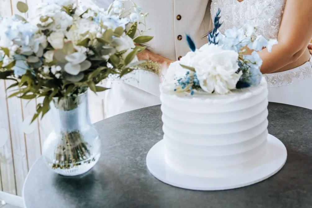 Modern white ridged buttercream wedding cake with white and blue florals