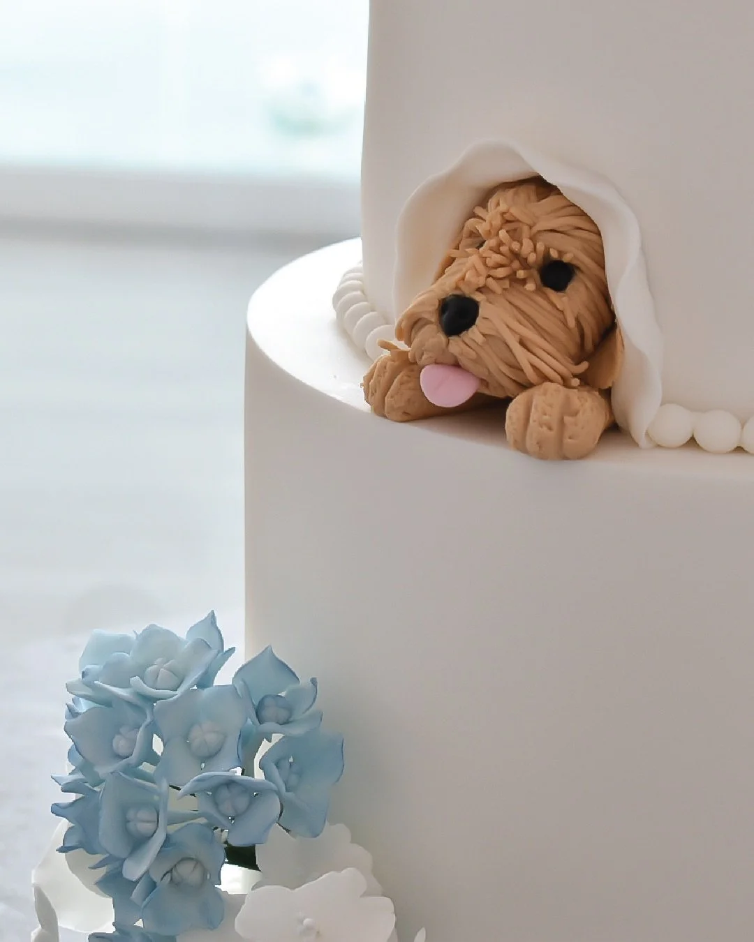 Handmade fondant cockapoo peeping out of wedding cake.