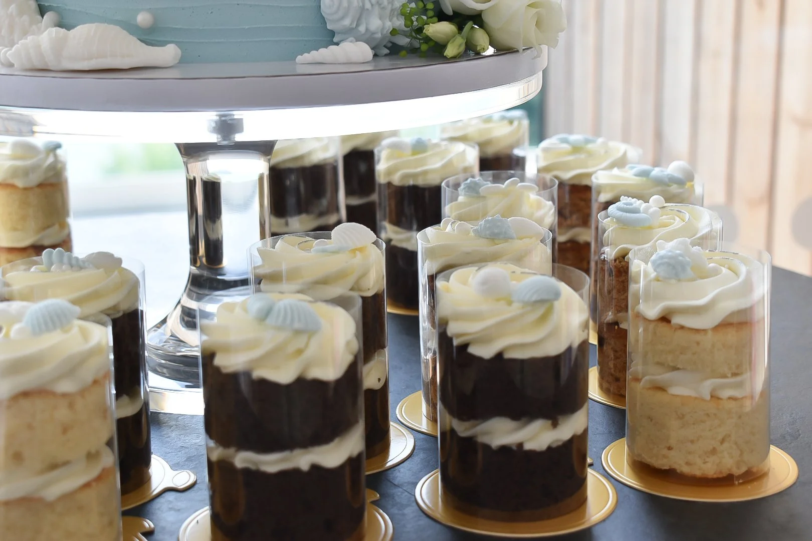 Wedding mini-cakes around a two tier beach themed buttercream wedding cake.