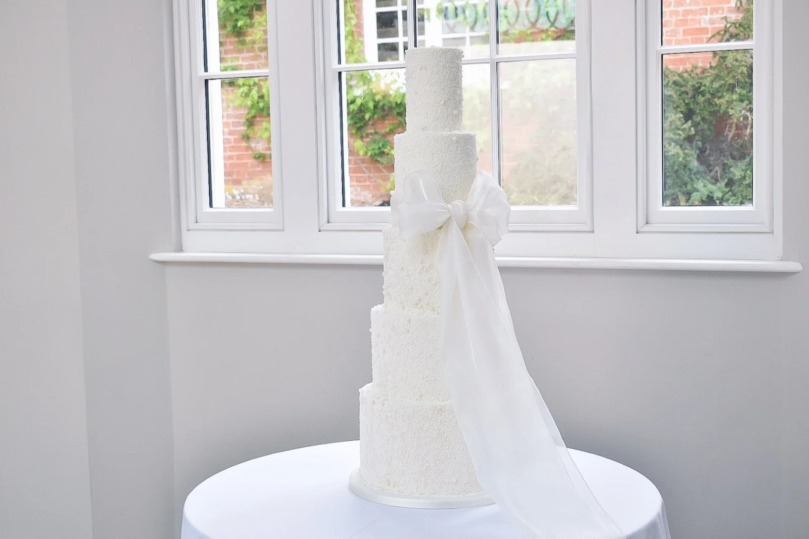 Five tier pearl wedding cake with large organza bow at Rockbeare Manor.